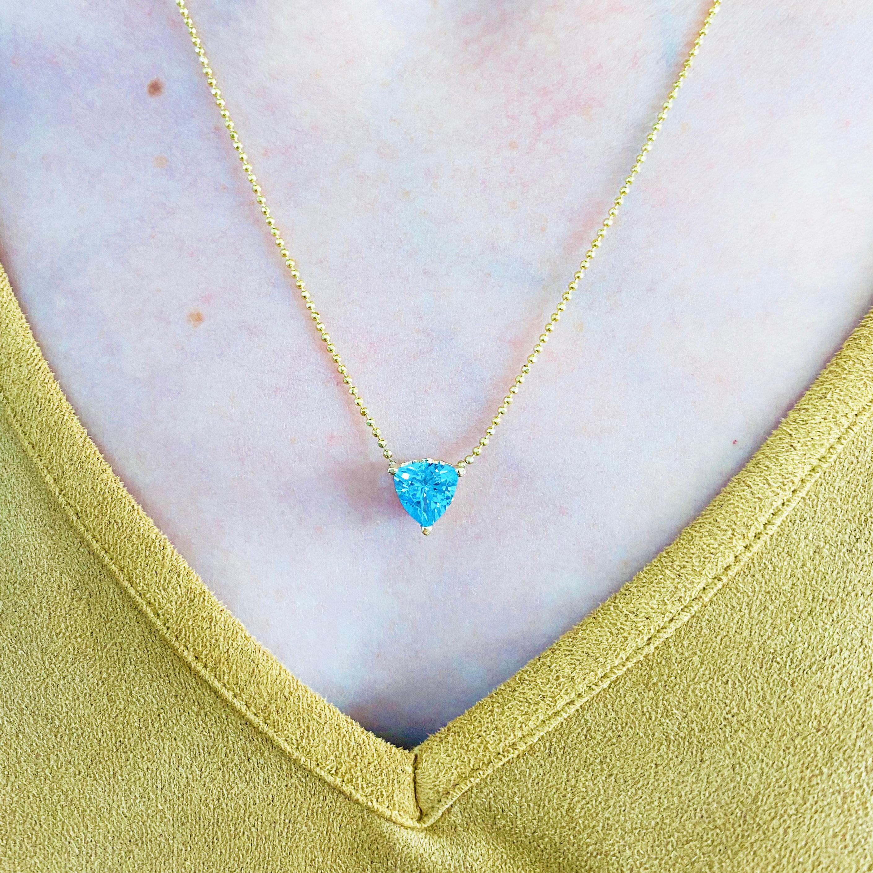 This beautiful vibrant trillion cut Swiss blue topaz set in polished 14k yellow gold was made in our shop by our goldsmiths and provides a look that is very modern yet classic! You won't believe how stunning this stone is. This necklace is made in
