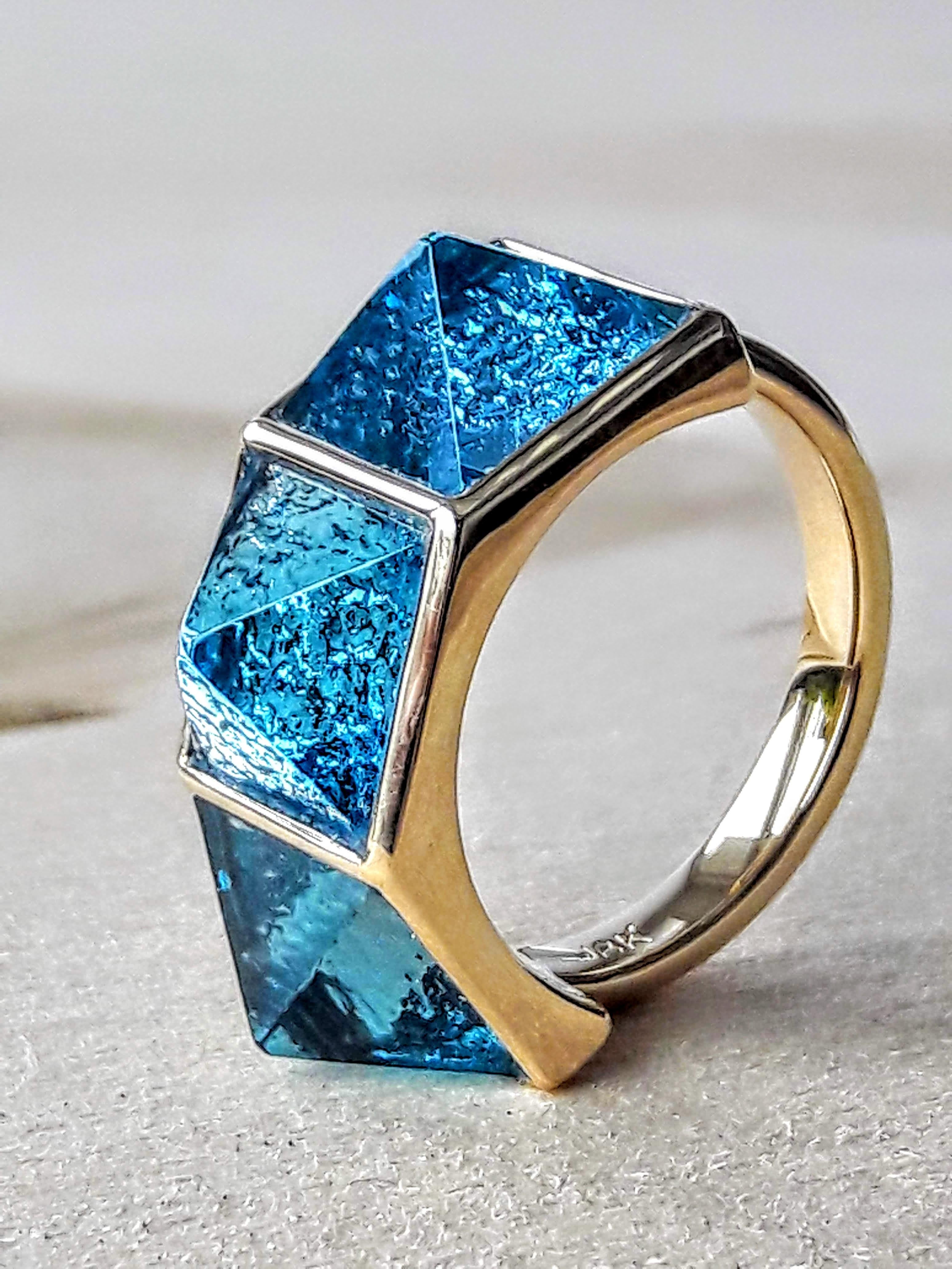 Pyramid collection, the Three Pyramids, swiss blue Topazes ring in 18k yellow gold, manufactured in New York.
This original collection of Pyramid cut, swiss blue topazes gems, set on top of hand work white gold surfaces representing the bottom of a