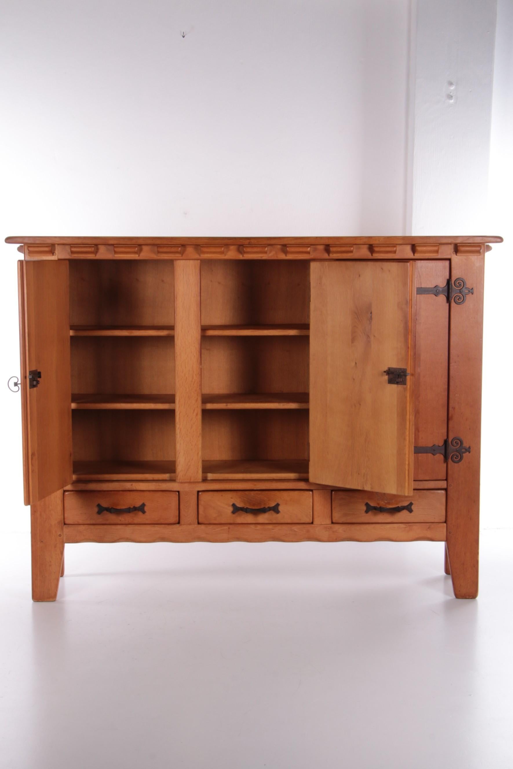 This is a beautiful and heavy oak cabinet or wall unit of good quality. Made in Switzerland in the 1970s.

Beautifully finished with wrought iron details and carved patterns in the wood. The warm color of the cabinet gives a cozy feeling to any