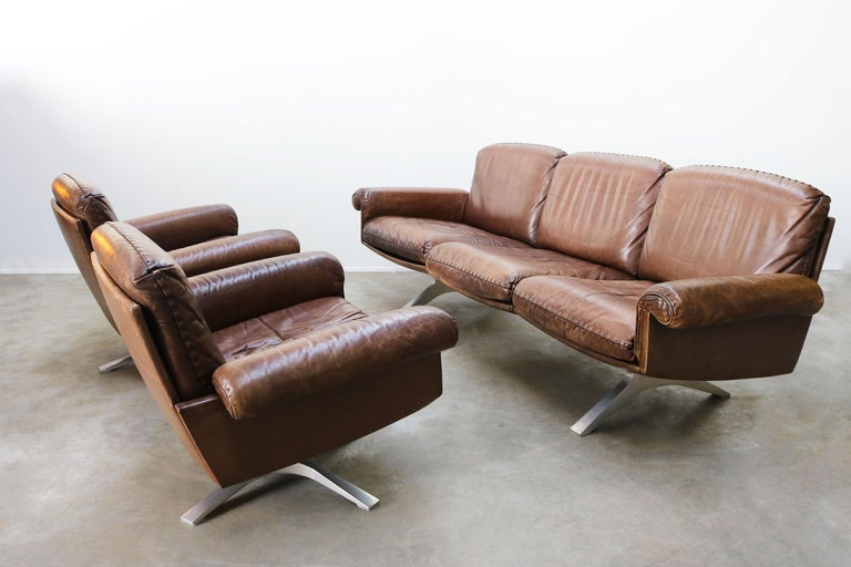 Rare and superb Swiss design living room set model: DS 31 designed by the world famous company: De Sede in the 1970s. 
The set consists of a three-seat sofa and 2 matching swivel armchairs in a magnificent light brown patinated aniline leather.