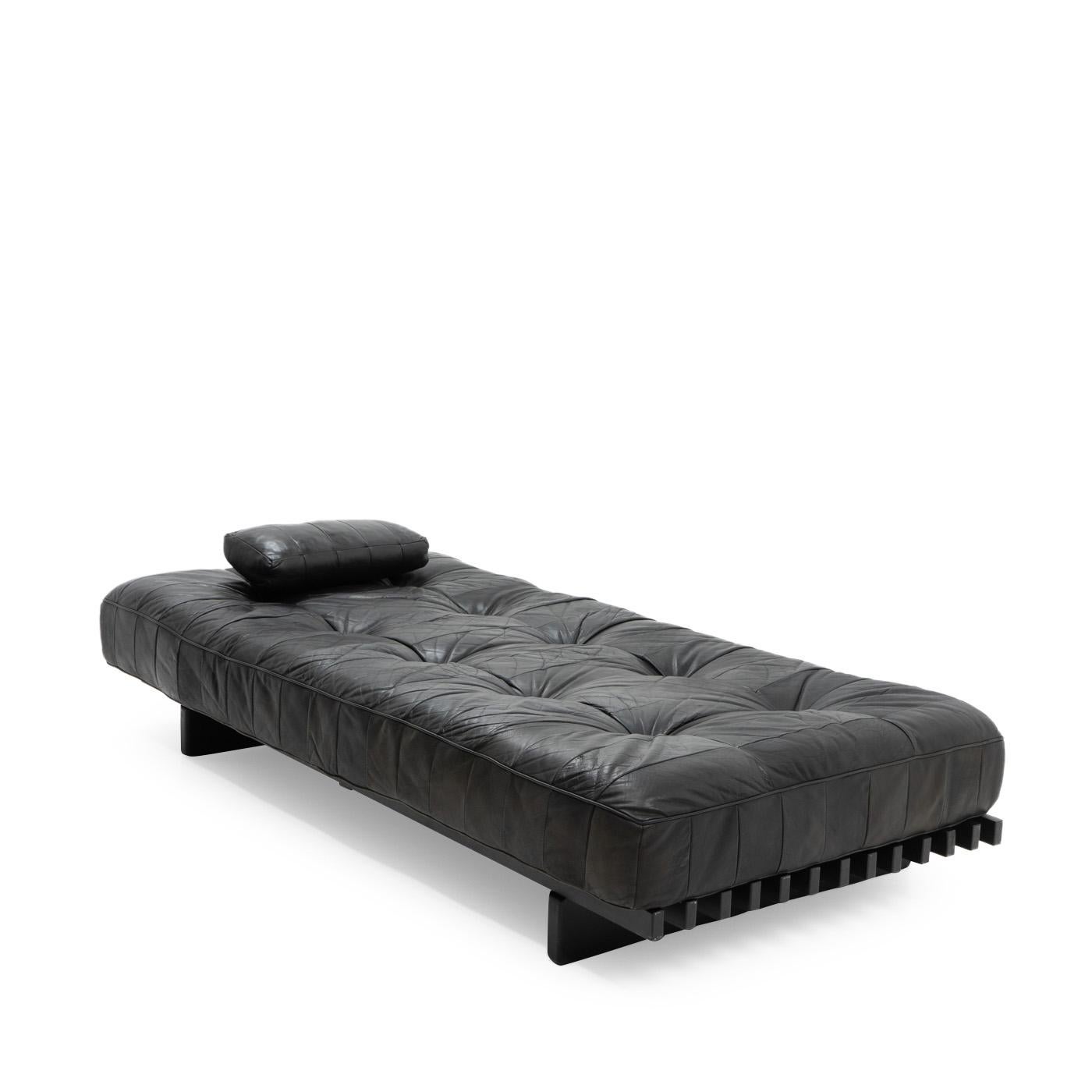 De Sede Daybed model DS-80 in beautifully patinated leather, featuring one pillow.

The leather is a patchwork design made from soft, black pigmented aniline leather, which typically gives a very lived look due to the open nature of the material.