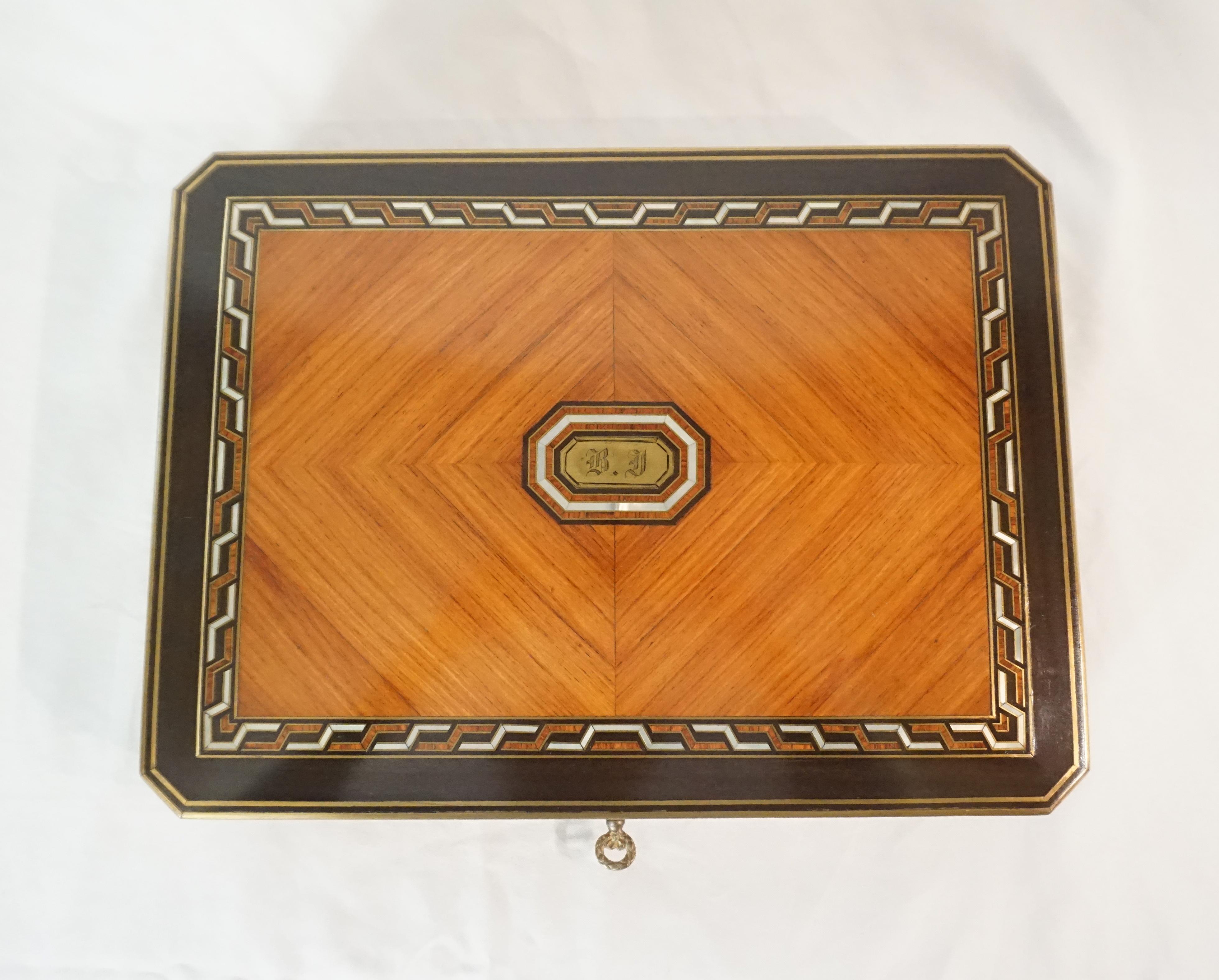 An exquisite Swiss, circa 1890, games box of rectangular form with canted edges; the slightly domed top with brass and ebony inlaid perimeters surrounding geometric nacre (mother-of-pearl), ebony, and brass inlaid border framing book-matched