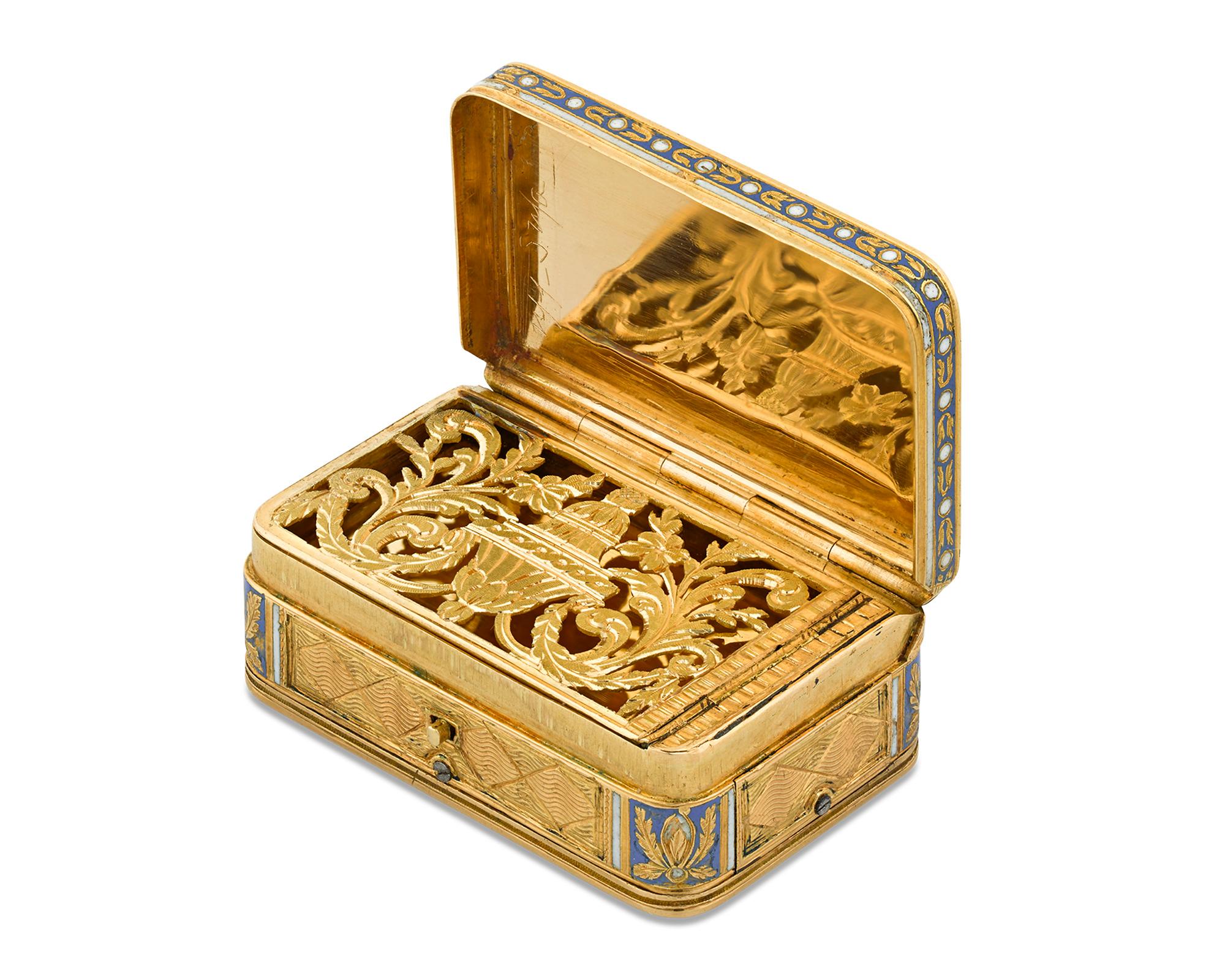 A musical movement distinguishes this wonderful early 19th-century gold vinaigrette box. The vessel is covered in delicate engraving highlighted by blue and white champlevé enamel detailed in a fine floral motif. The button on the front of the box
