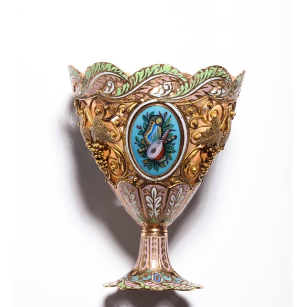 A Swiss gold and enamel Zarf for the Turkish Market, circa 1840,  

of vase form with waved rim, decorated with three oval painted panels of flowers, divided by gold filigree of grapes and vines.  

Measures: 2.5