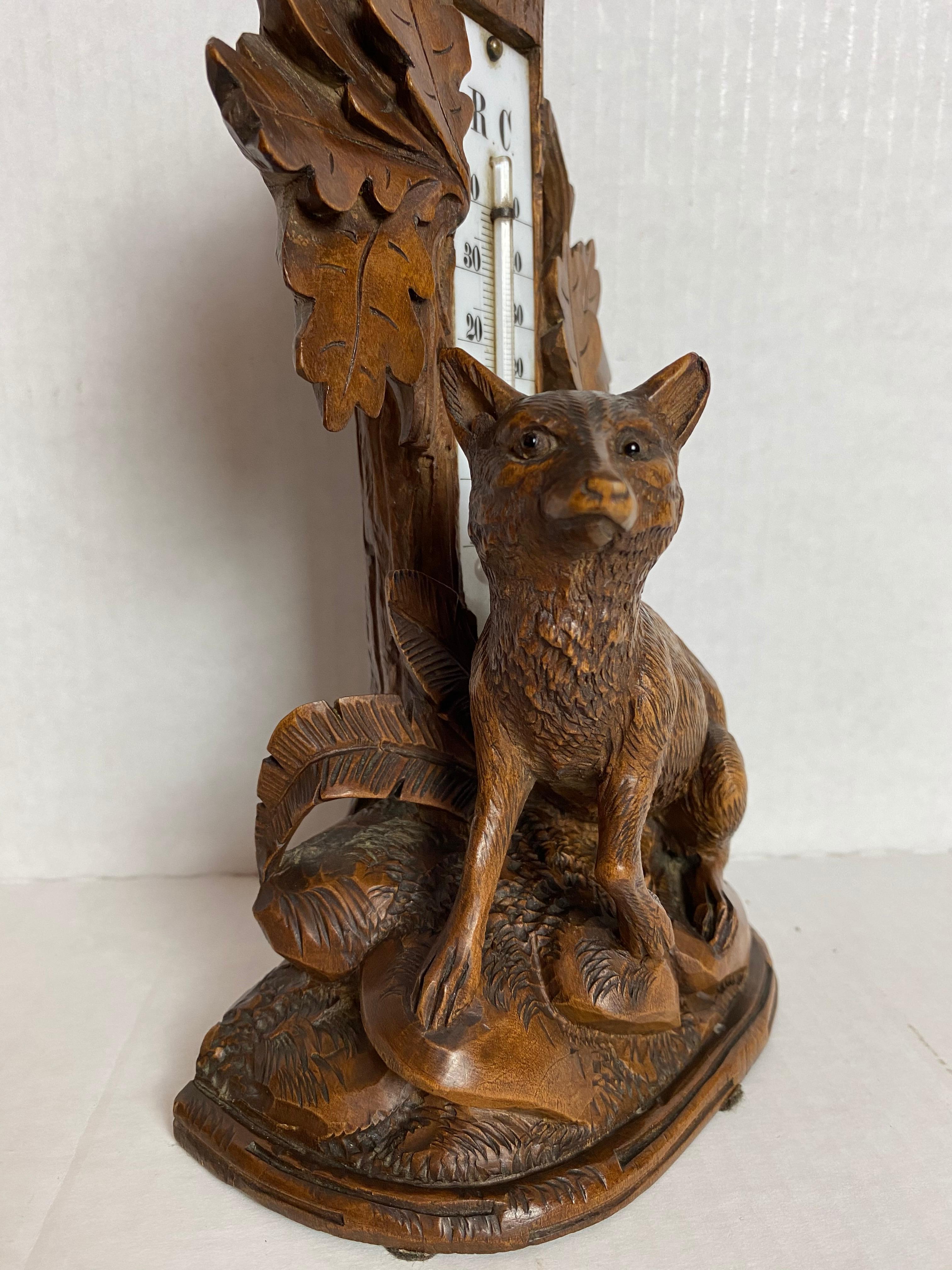 Swiss hand-carved Black Forest figure of a fox with thermometer, Brienz, Switzerland, circa 1880 in linden wood, with the original antique thermometer, with readings for C--Celsius and R--Rankine, inset to a naturalistically carved tree trunk,