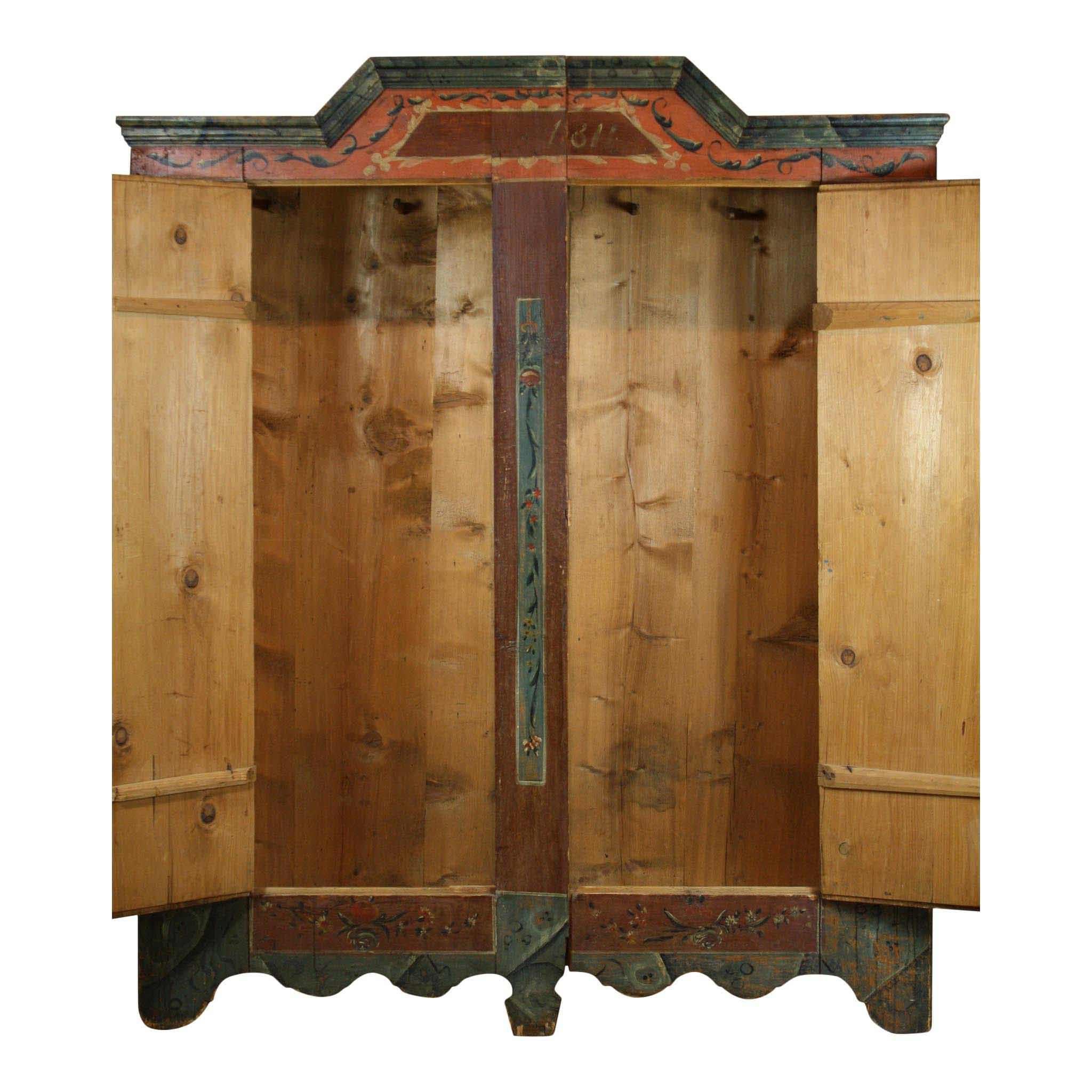 Dated 1811, this two-door armoire is beautifully hand-painted with a floral motif in rich, warm shades of green, orange, and brown. The top is crowned with an angled pediment. The base is trimmed with scalloped edges. Inside the wardrobe, there are