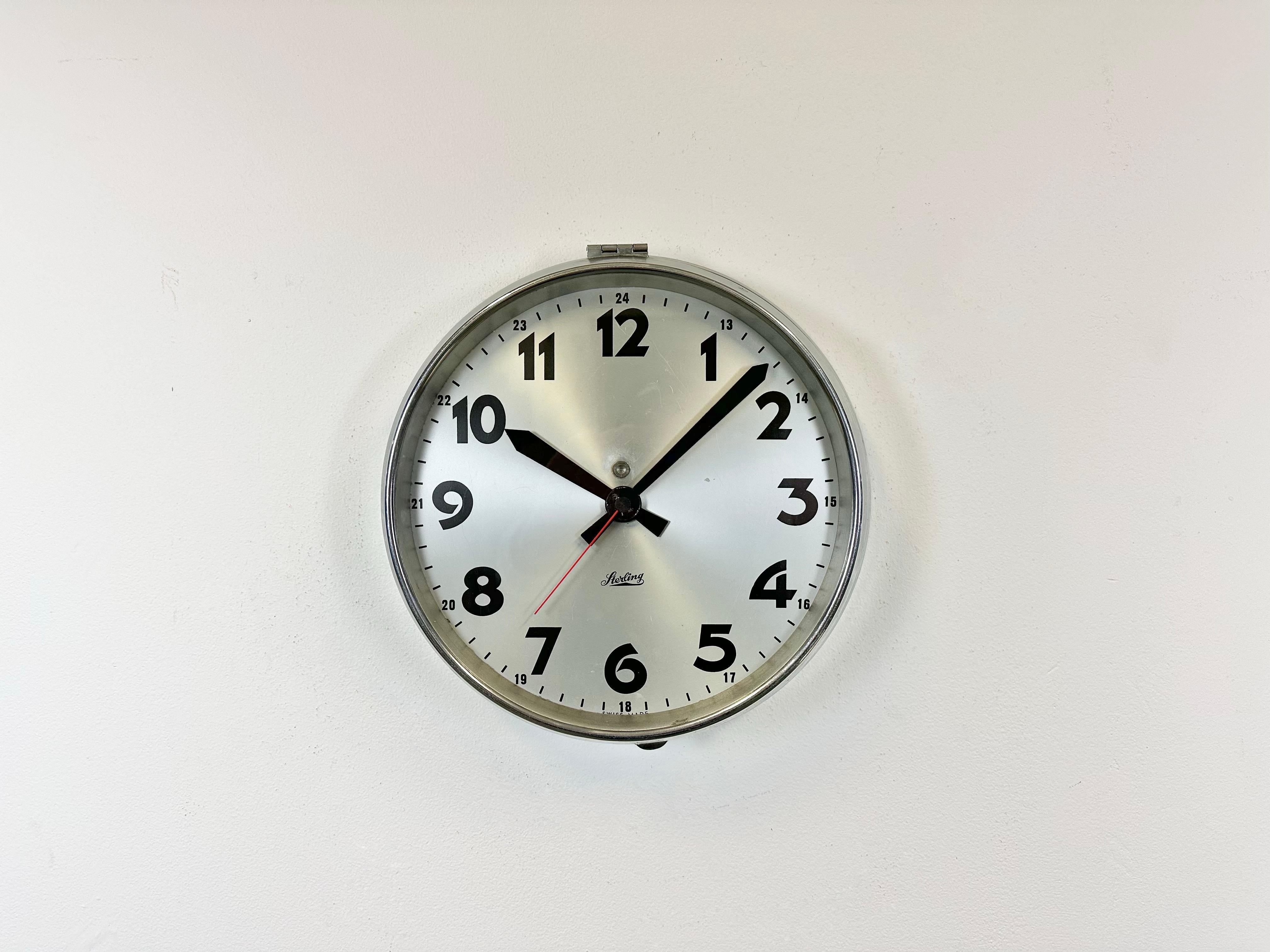 Vintage Industrial wall clock made by Sterling in Switzerland during the 1960s. It features a metal chrome plated frame, a silver metal dial, an aluminium hands and a clear glass cover. The piece has been converted into a battery-powered clockwork