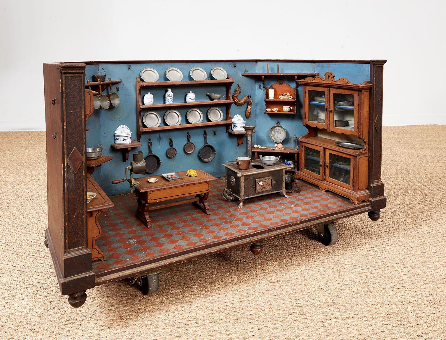 A large hand-made model of a Swiss kitchen circa 1910, in a walled surround with canted corners and turned feet, having exquisitely detailed furniture, appliances and fittings crafted of pewter, iron, copper, ceramics and wood to scale, including
