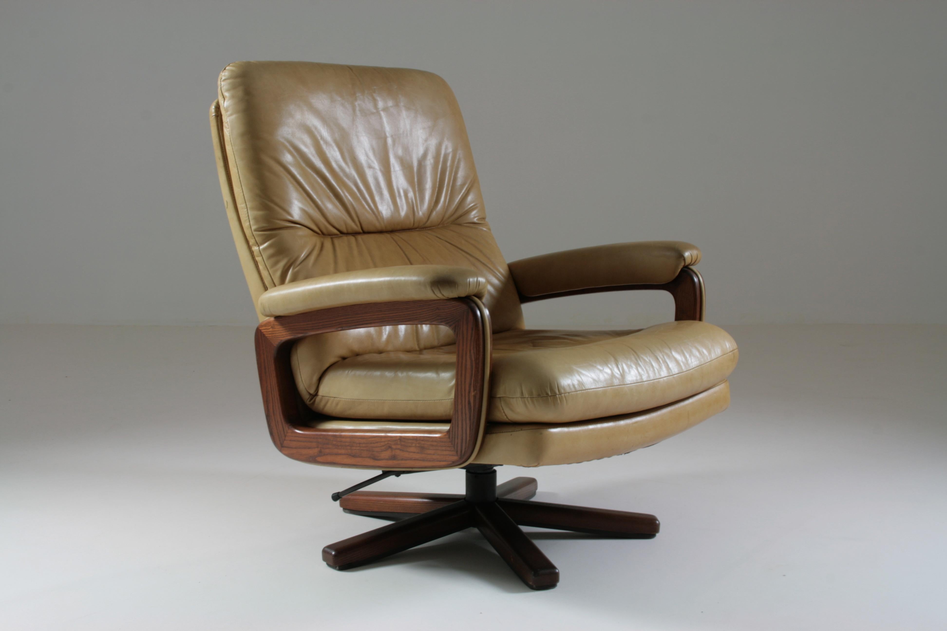 Swivel and reclining lounge chair designed by André Vandenbeuck, manufactured by Strässle in Switzerland. Central legs in metal and wood providing a perfect seat on the ground. Beige leather upholstery with a nice patina. Note a small tear on the