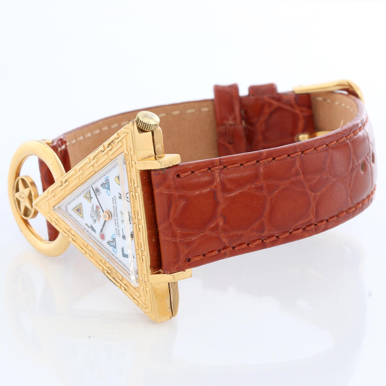 Schweizer Freimaurer Dreieckige Armbanduhr - Handaufzug. Gehäuse aus Gelbgold (40 x 47 mm). Weißes Zifferblatt mit freimaurerischen Stundenmarkierungen und der Aufschrift: Liebe deinen Mitmenschen, gib ihm eine helfende Hand, äußere Minuterie und