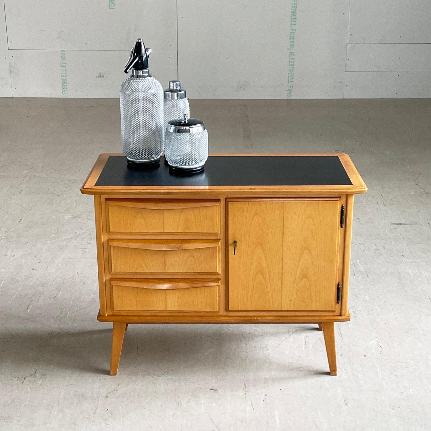 Mid Century Drinks Cabinet (Ende der 50er - Anfang der 60er Jahre).
Schöne Schränke. Außen aus Buchenholz, innen aus Ahorn. Tischplatte aus geschwärztem Glas. Drei Schubladen mit abschließbarem Ablagefach für Flaschen und Glasboden. Perfekt für die