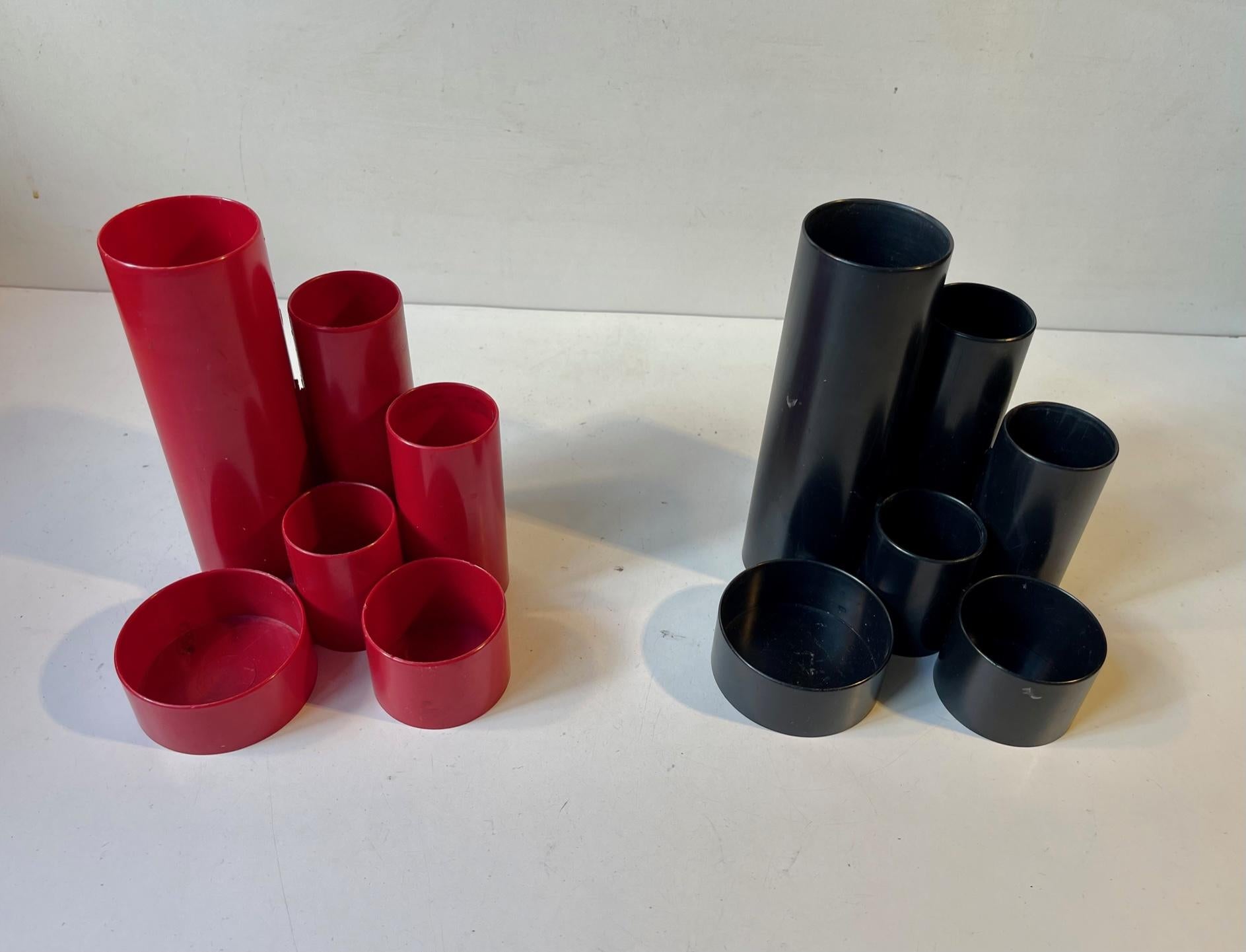 A red and a black pencil-holder in cast acrylic. 1970s Modern architectural styling. Designed and manufactured by Pentex in Switzerland. Each with 6 cylindrical compartments for utensils, scissors, clips etc. Measurements: H: 15 cm, W: 14 cm, Dept: