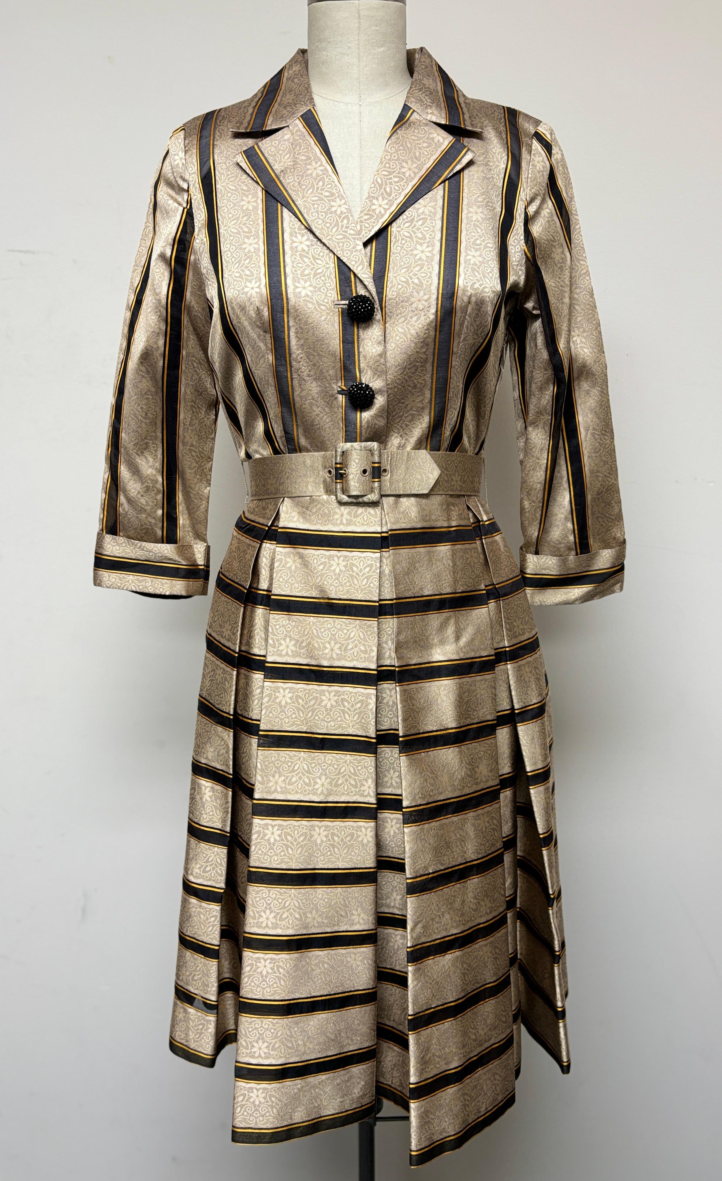 100% seda suiza, un divertido vestido camisero a rayas en negro y dorado es un hallazgo lujoso y único. Un tejido de seda realmente bello, cuyo diseño a rayas le da un aspecto juguetón y elegante. Con su cinturón de seda a juego, este vestido es