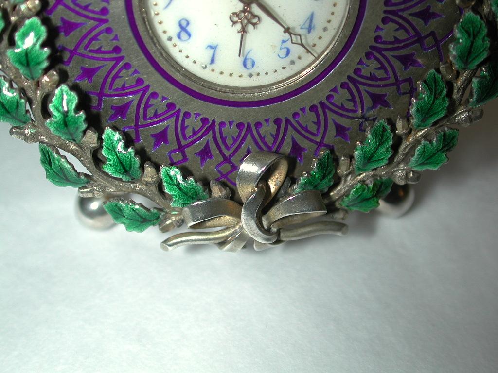Swiss silver and enamel dressing table clock, circa 1900
Beautiful travelling silver clock with silver struts at the back which fold away for packing.
With a green laurel leaf enamel border and a blue enamel inner border.
Made in 800 standard