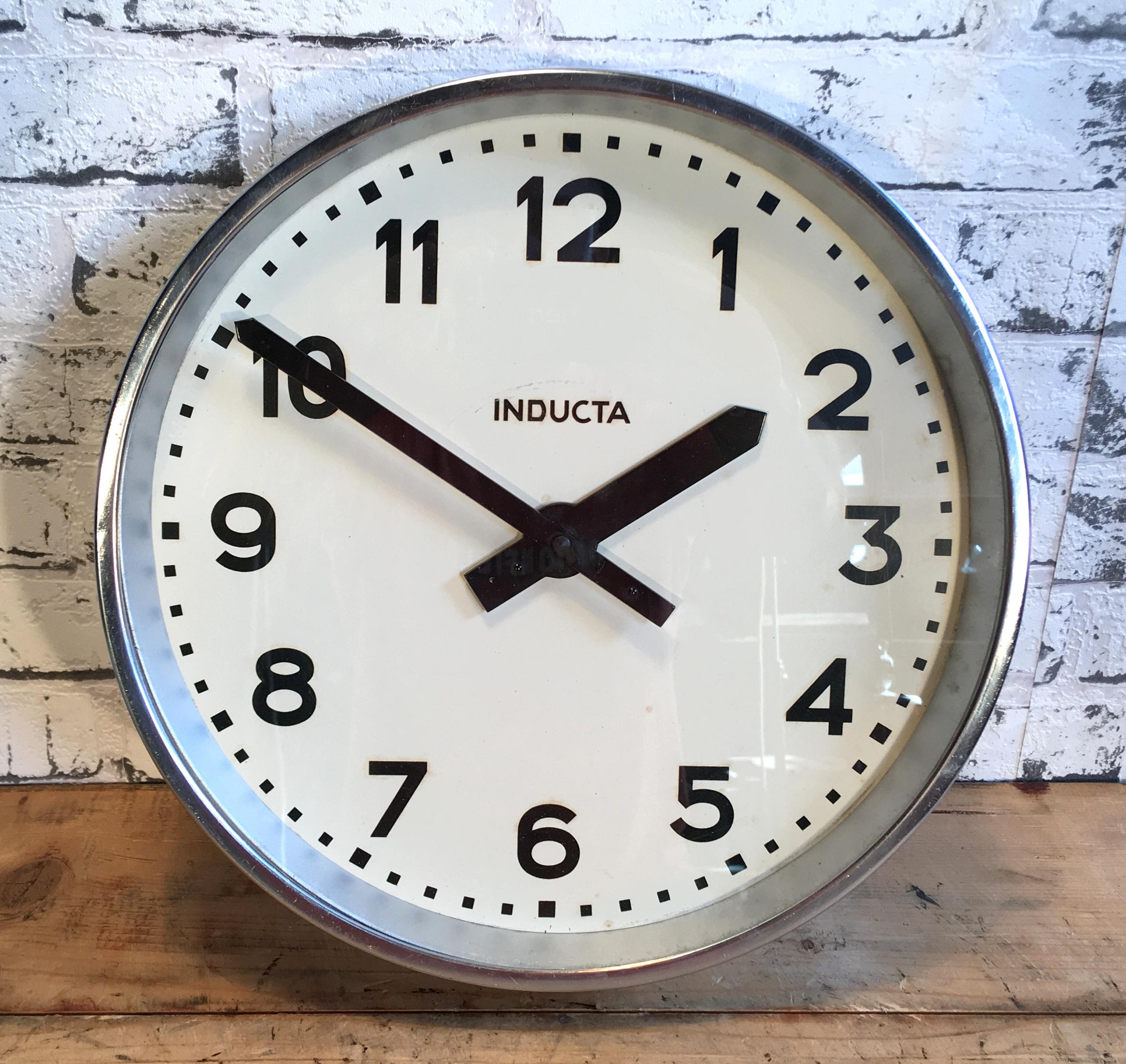 This wall clock was produced by Inducta in Switzerland during the 1970s.It features a chrome plated metal frame and clear glass cover. The piece has been converted into a battery-powered clockwork and requires only one AA-battery.