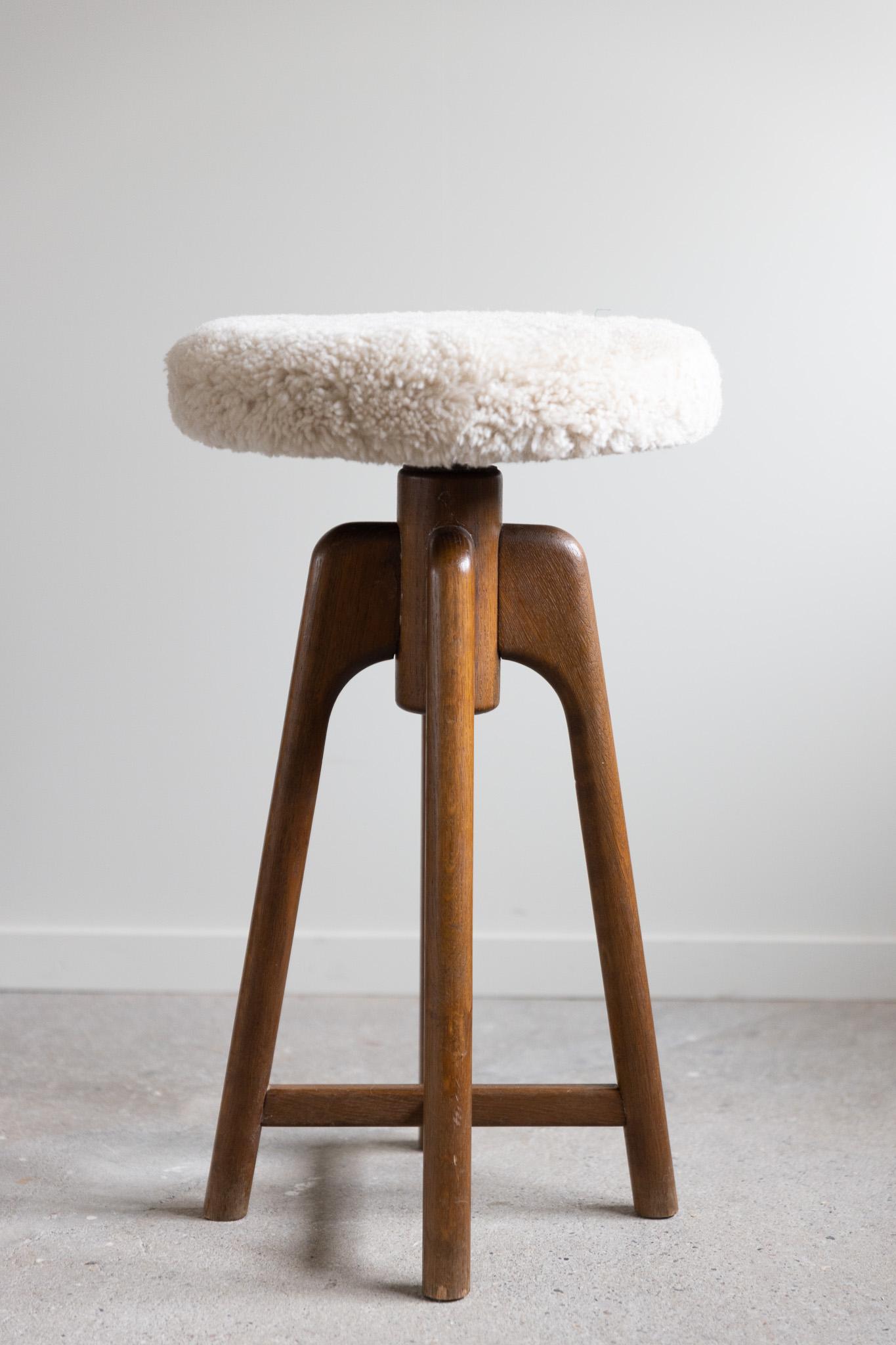 Beautiful bar stool in stained oak and reupholstered seat in great quality shearling lambswool. This decorative piece of design has an adjustable and rotating seat which can reach the seat height from 66 cm to 82 cm. Its elegant shape and warm