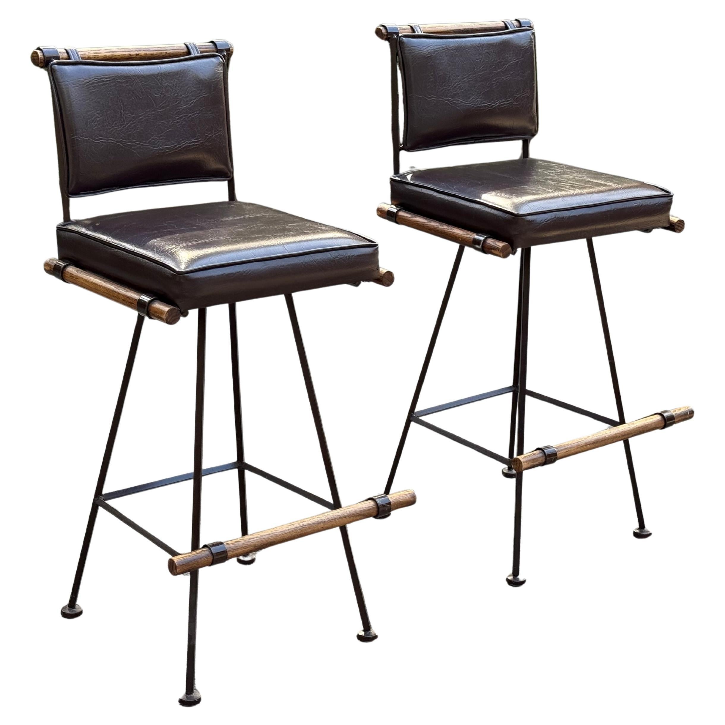 A pair of classic mid-century brown leather swivel bar stools for Inca Products, USA, circa 1960s in the style of the legendary Cleo Baldon. 

Price is for the pair.

This vintage pair feature wrought iron frame with lattice seat backs and brown