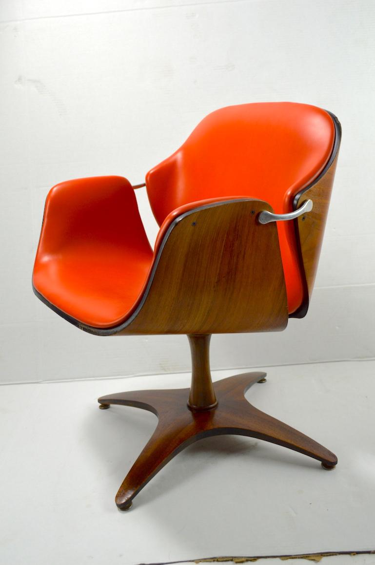 Rare and unusual form not often seen, designed by George Mulhauser for Plycraft. Swivel upholstered chair in orange vinyl with bent ply shell, cast aluminium joinery, on pedestal base. Chair shows minor cosmetic wear, scuffs and minor nicks, normal