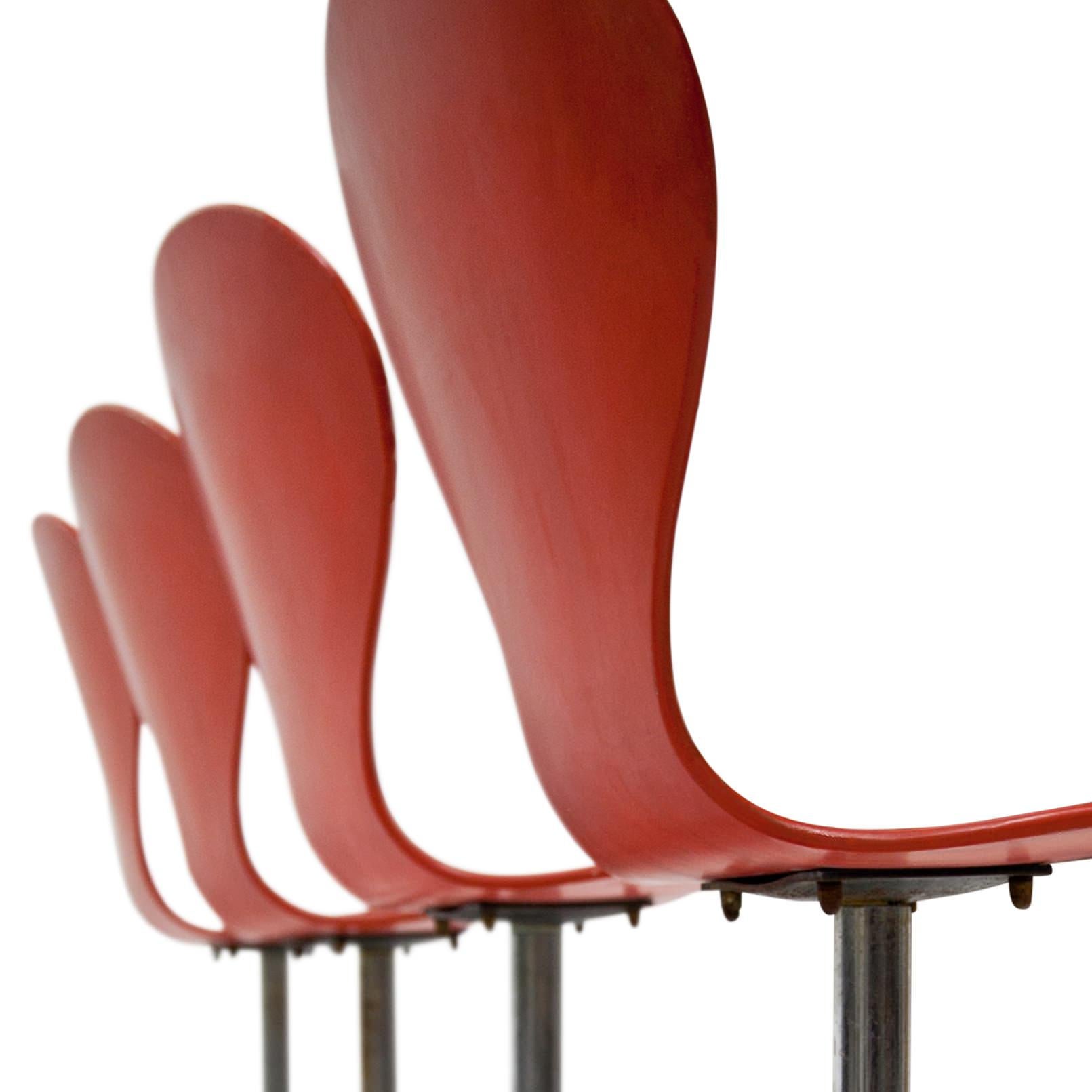 Set of four swivel chairs with red seats and a chromed metal base. The seats are labeled “benze Sitzmöbel und Tisch” and show some signs of age and use.