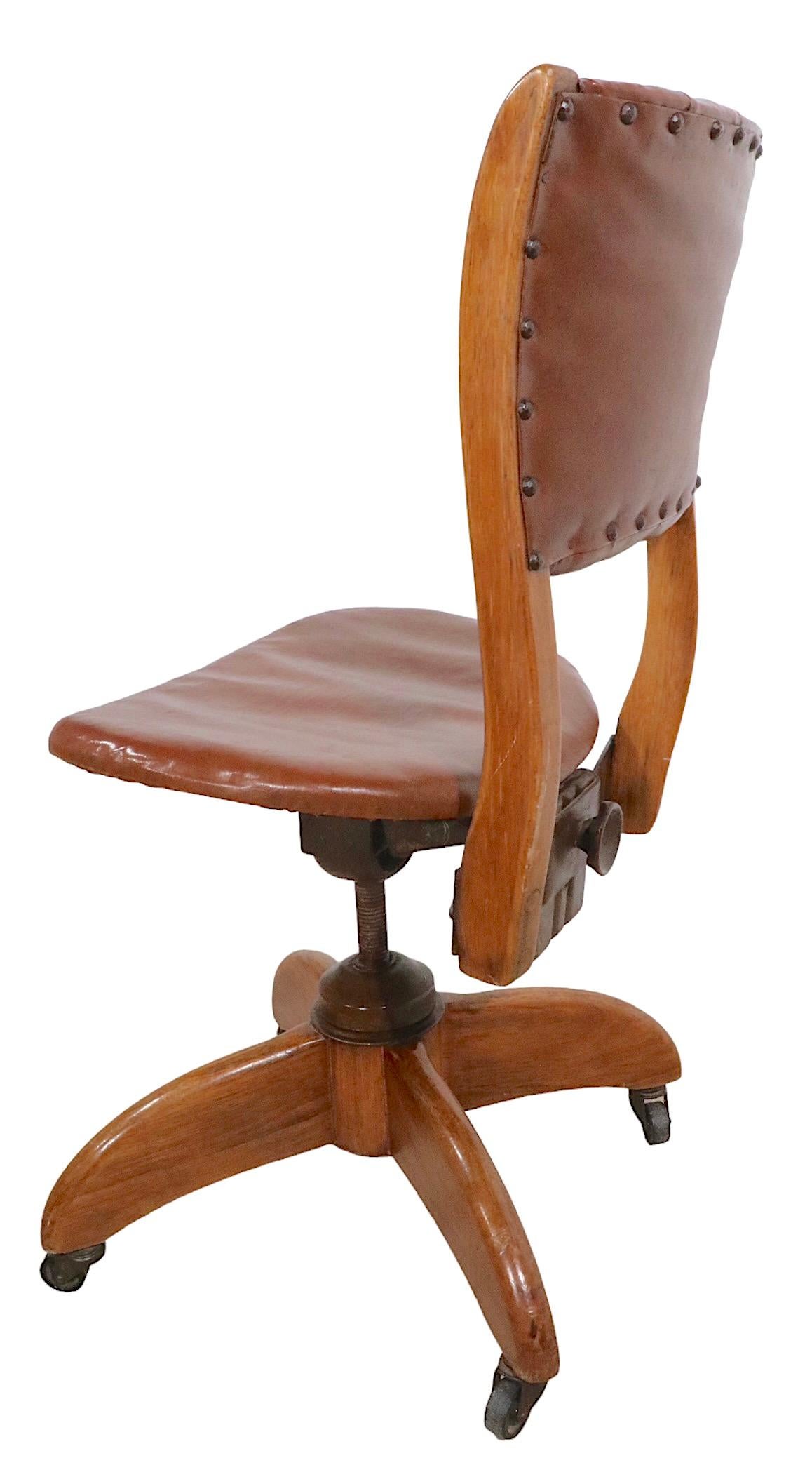 Exceptional example of a classic swivel desk, office, task chair by noted American maker, Gunlocke. The chair is in very fine, original, clean and ready to use. The frame is of solid wood, the upholstery is vintage ( original ) oilcloth. The seat