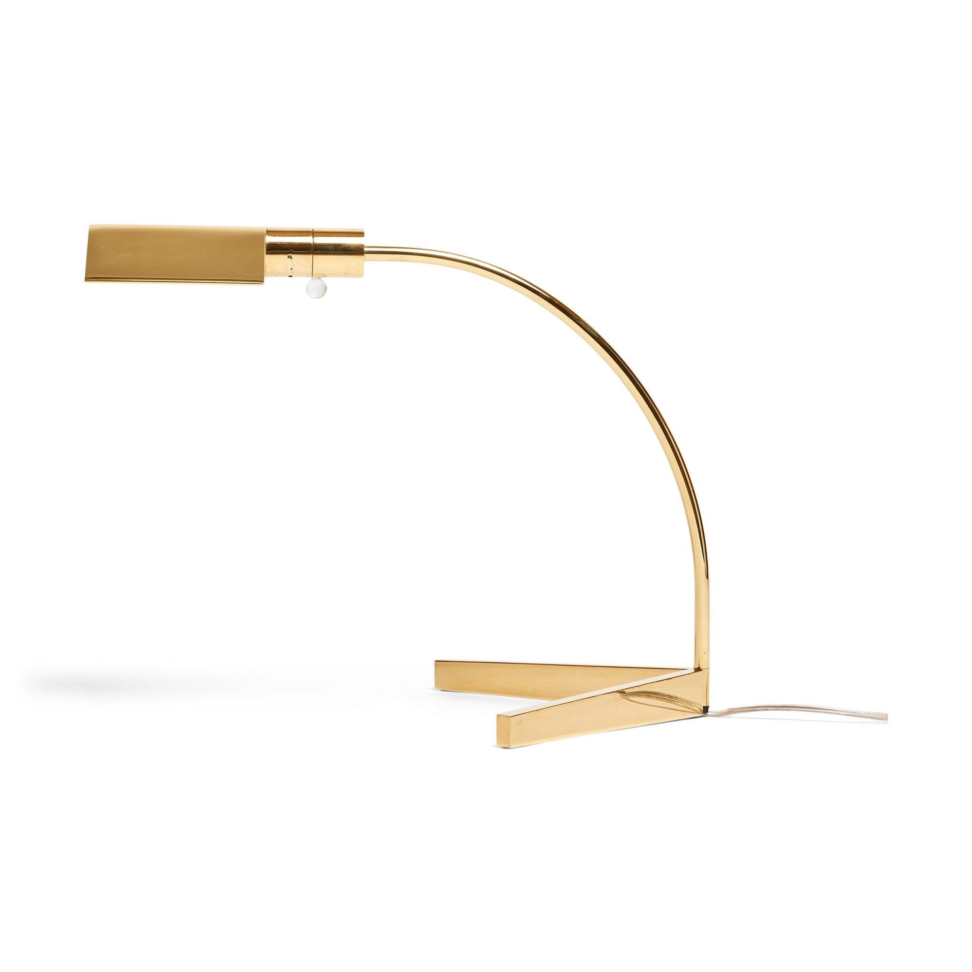 A finely machined desk lamp in brass having a single curved pivoting arm on a forked base with a dimmable round lucite switch.
