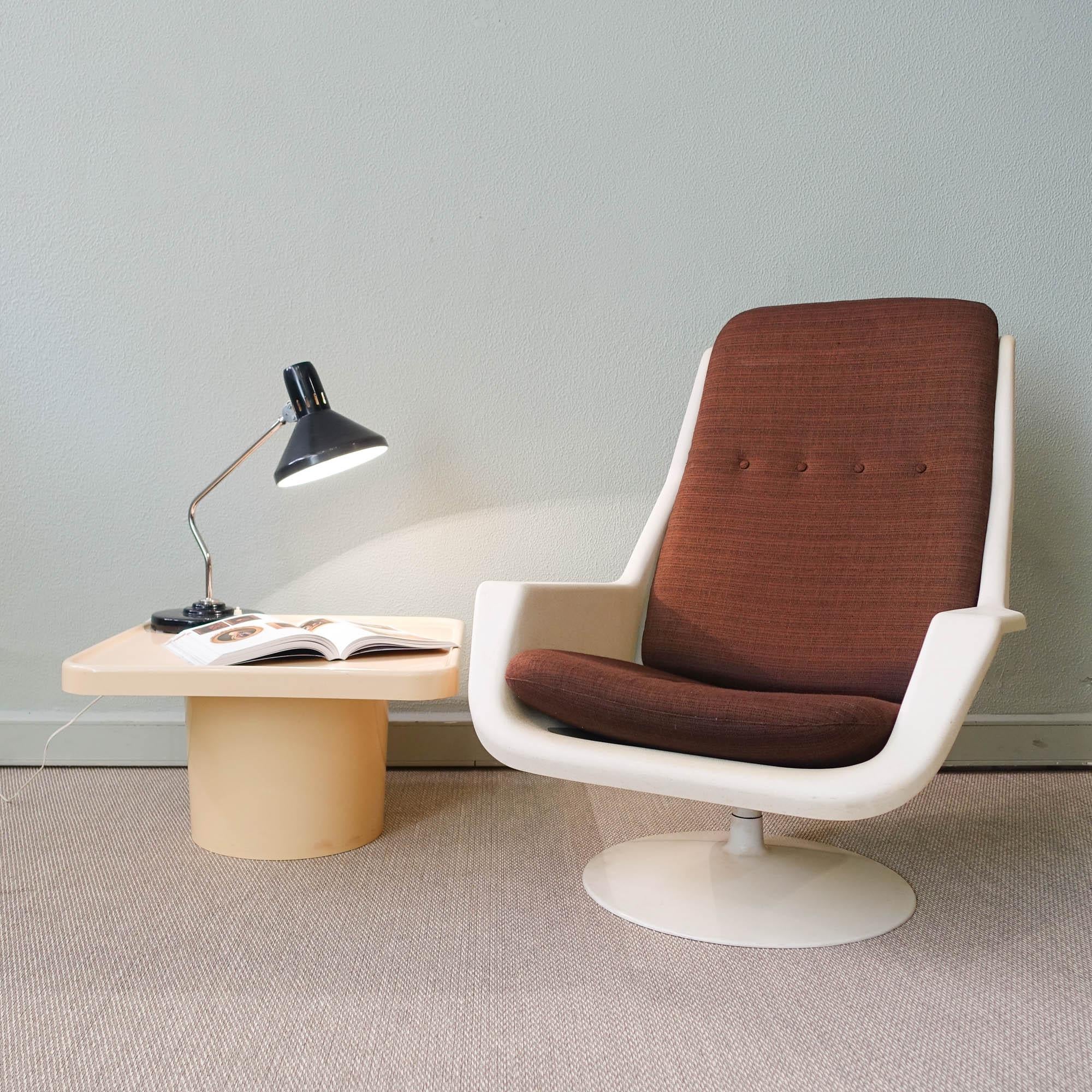 This set of lounge chair and side table was designed by Robin Day for Hille, in UK, during the 1970's. The lounge chair is a polypropylene frame that stands on a metal circular swivel base. It is in a used condition with some scratches here and