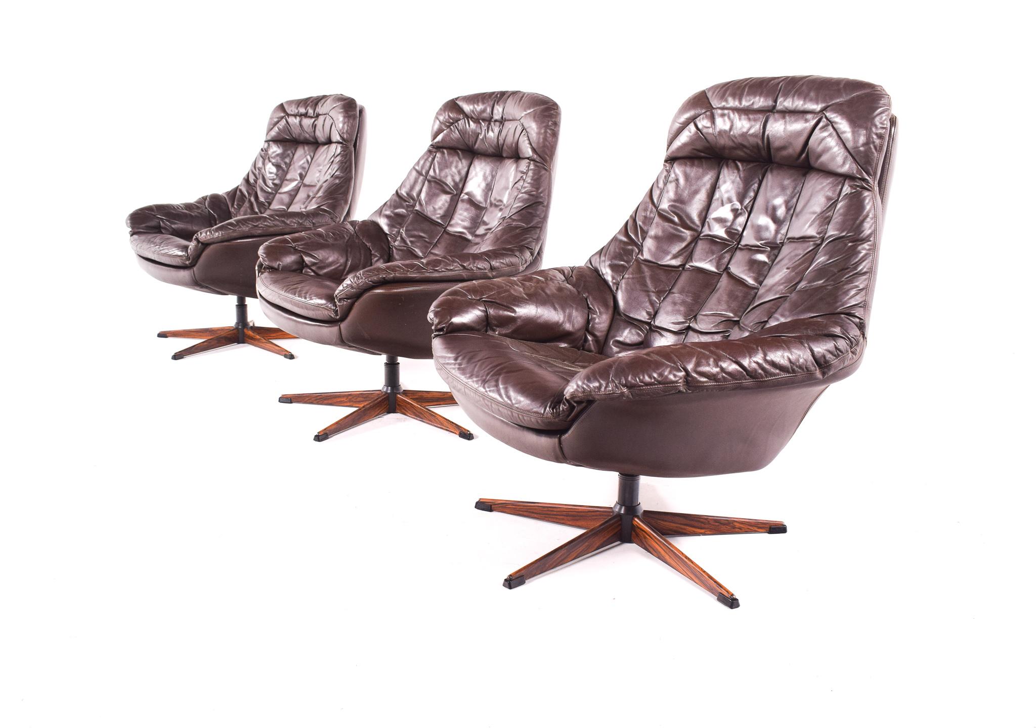 Designed in 1960s for Bramin by Henry Walter Klein, this is a set of three Danish Swivel lounge chair with a floating base with rosewood veneer feet. The upholstery is in original brown colored leather. Comfortable chair with good proportions.