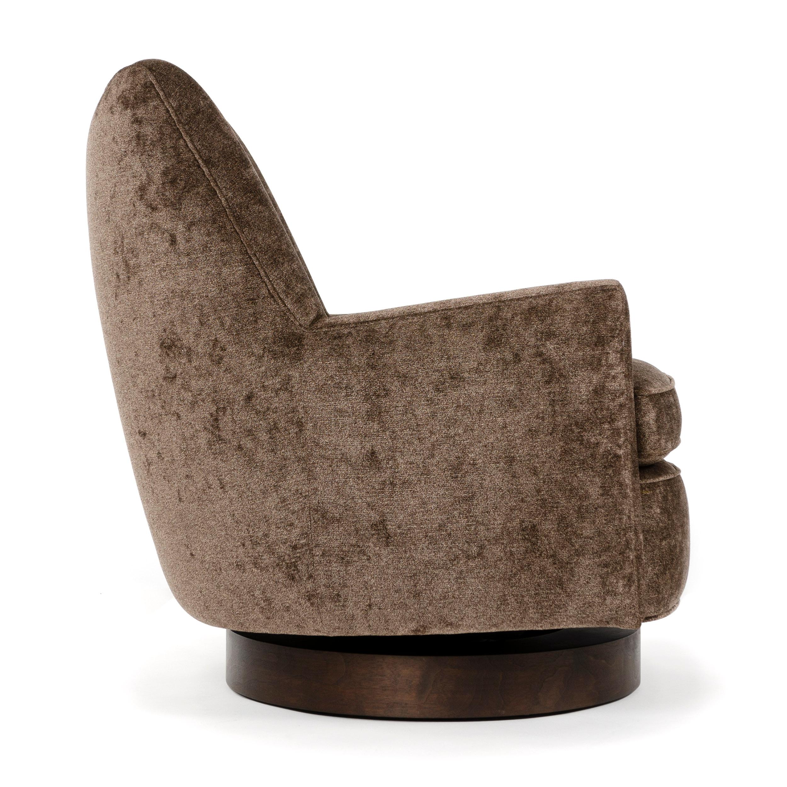 A swivel lounge chair on an ebonized ash disc base. Newly upholstered in brown chenille.