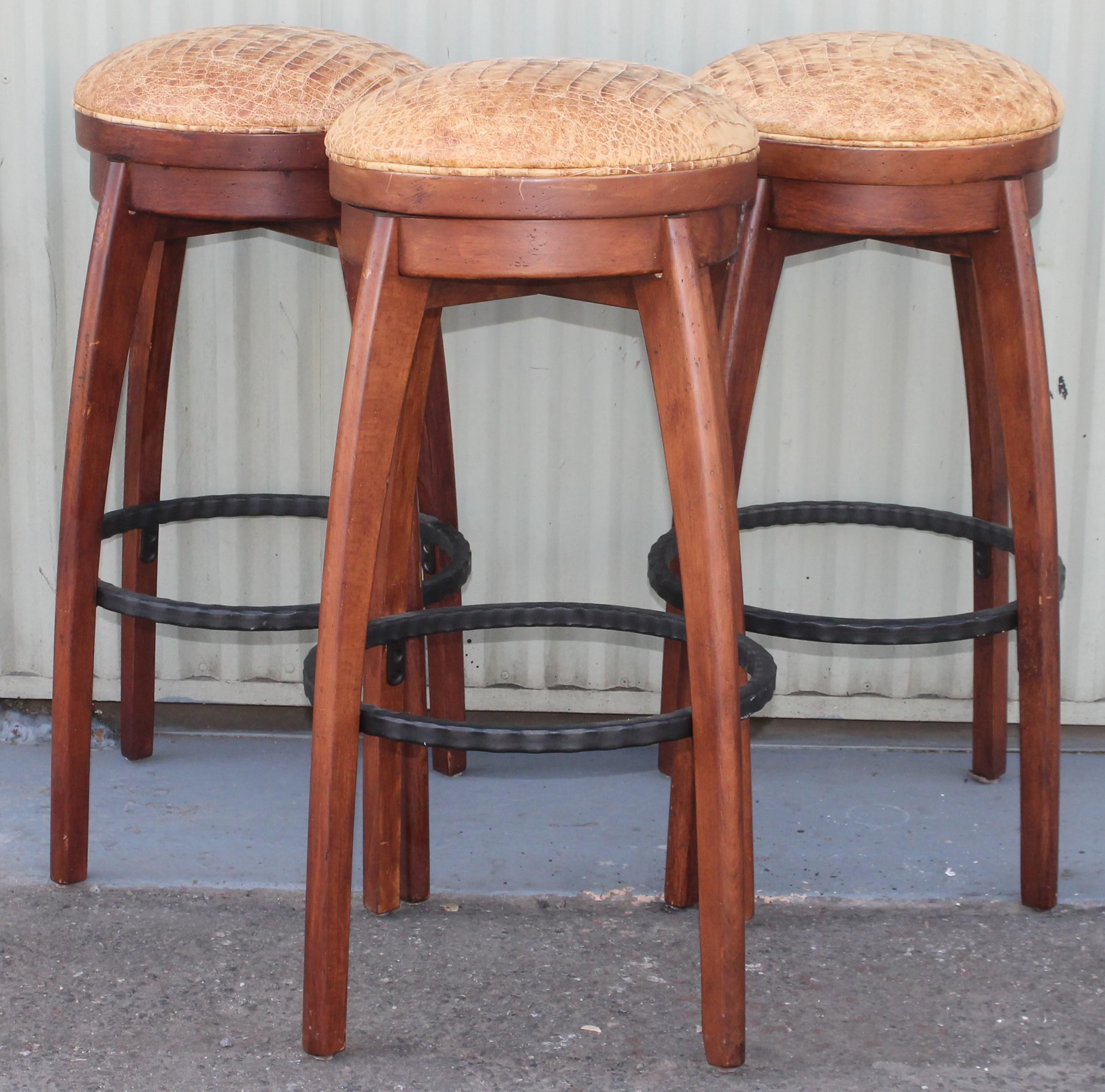 These amazing Mid-Century Modern walnut bar stools are in Fine condition and have a newly distressed leather seats and swivel as well. Sold as a set of three. We also have two others in inventory. Can purchase three or five stools.