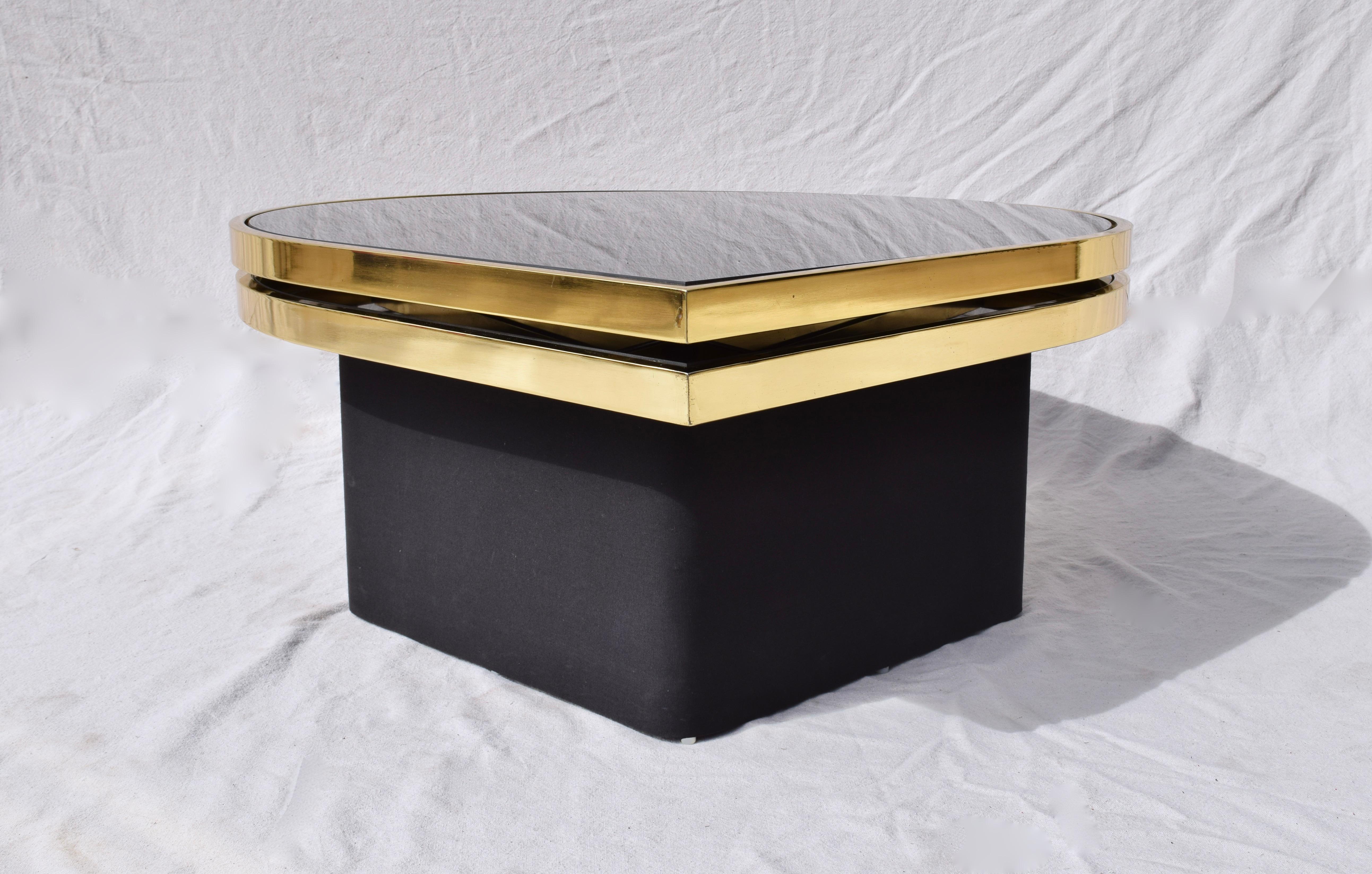 Elegant reverse black painted glass and brass cocktail or coffee table with floating upholstered base designed and manufactured by Richard Barry for Design Institute of America (DIA). The top of two striking teardrop surfaces swivels smoothly
