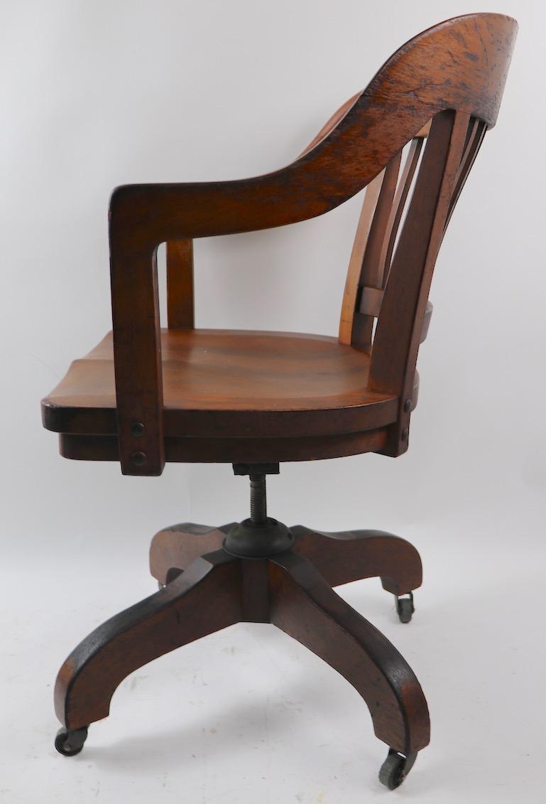 Classic swivel, tilt desk chair in solid walnut. This example adjusted in height as follows:
Total H in extended position 37 x seat H 20.5.
H in low position 34 x seat H 17 inches.
The chair also swivels full 360 degrees, and tilts to provide