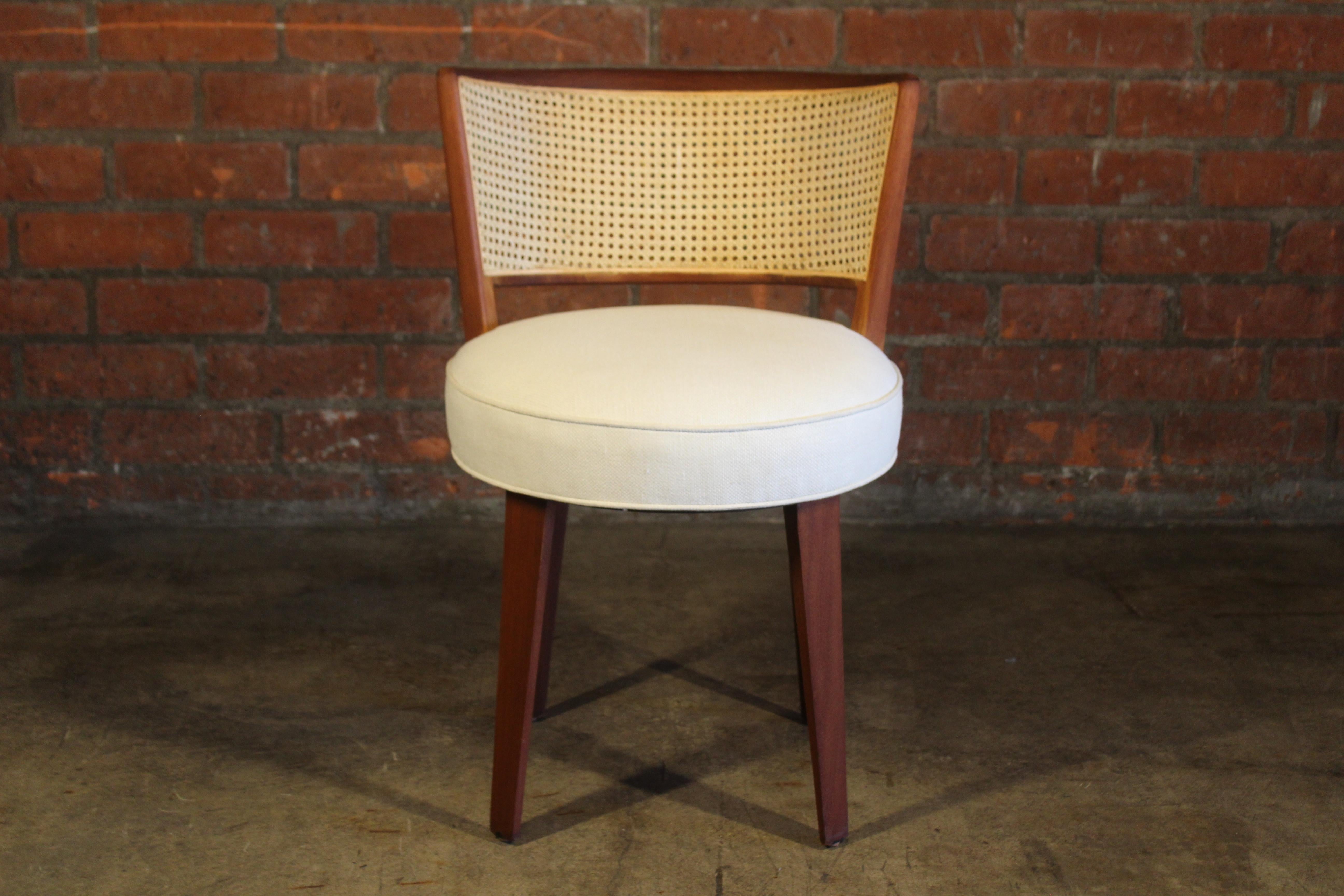 A vintage 1950s swiveling vanity chair designed by Edward Wormley for Dunbar. Completely restored. Newly refinished, new caning and new upholstery in an off-white Belgian linen. Overall wonderful condition.