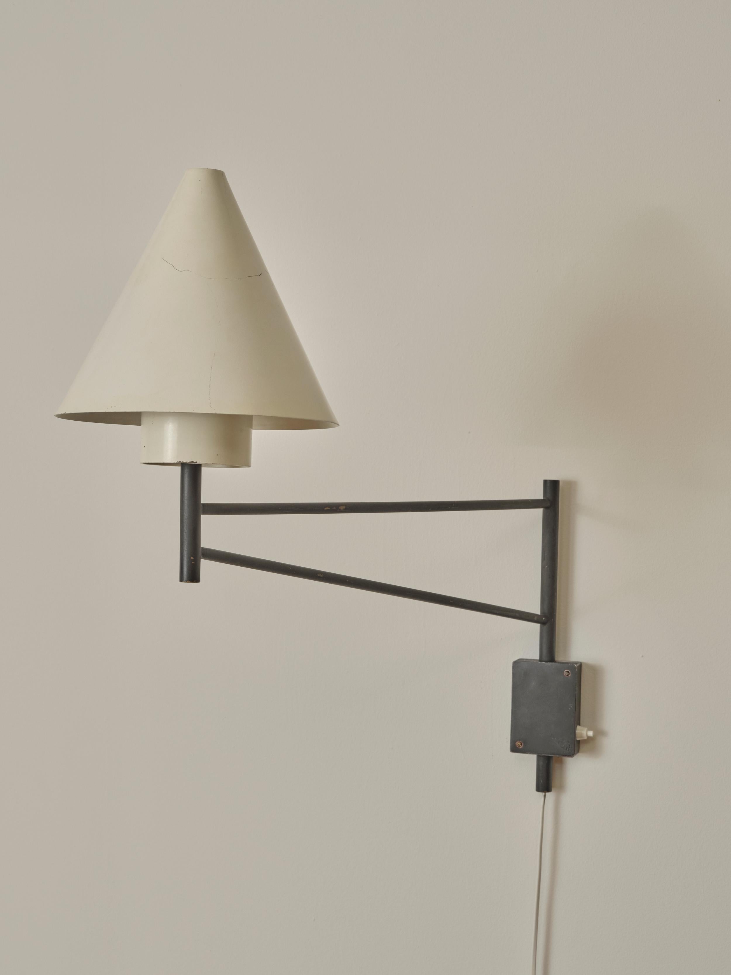 Swivel Wall Lamp attr. To Eje Ahlgren for Luco. Its core elements include a sturdy metal swivel arm and a white cone-shaped metal shade. The cone-shaped metal shade helps direct and diffuses light effectively. 