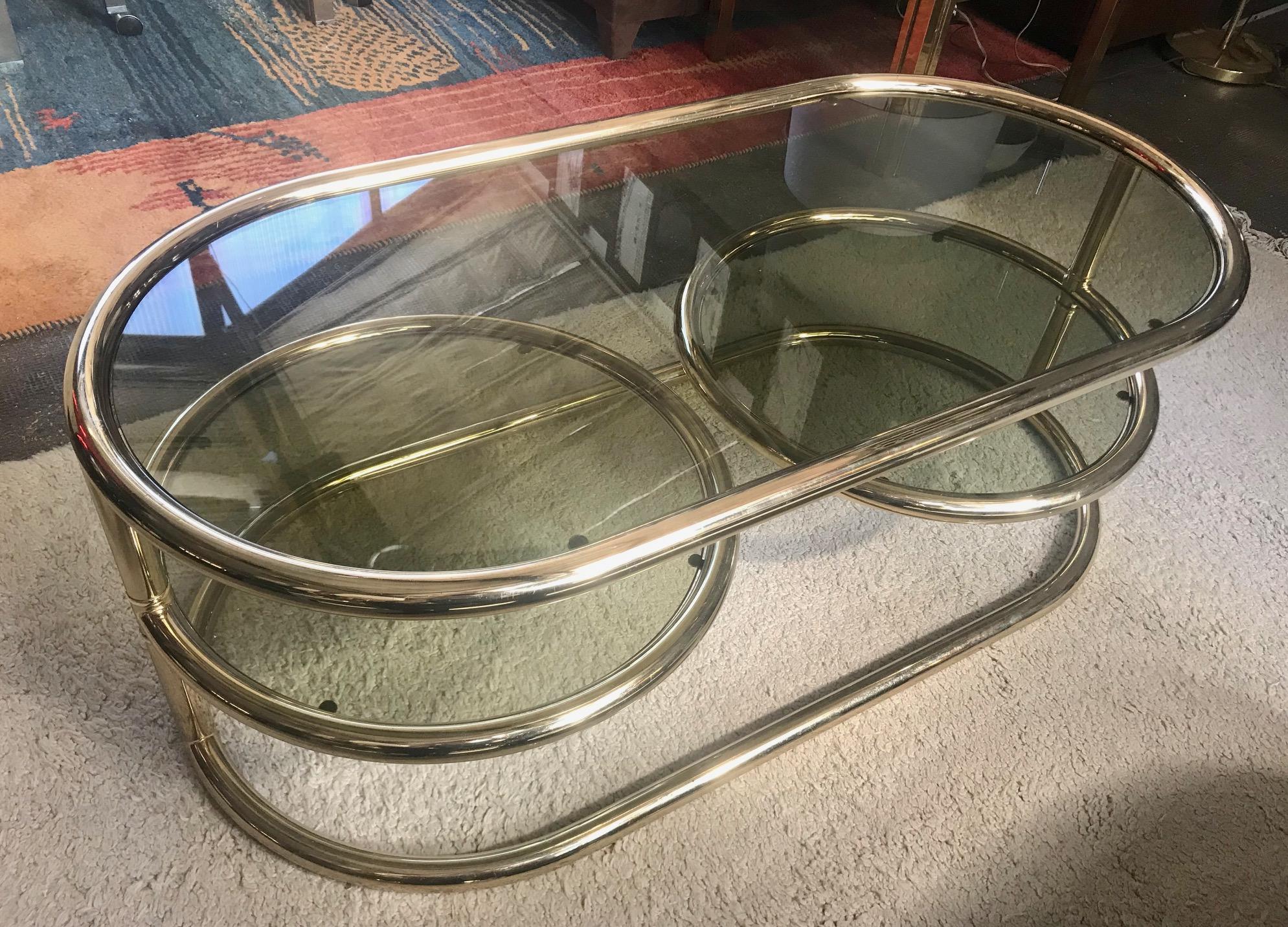 Swiveling coffee table, brass-plated, smoked glass top with two revolving glass plates.
Date of manufacture 1970.
