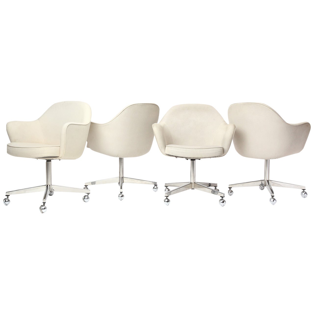 A Mid-Century Modern sculptural swiveling armchair designed by Eero Saarinen featuring a cruciform chromed steel base with casters. The seat retains its original textured wool upholstery in cream and floats atop a central column. Made by Knoll in