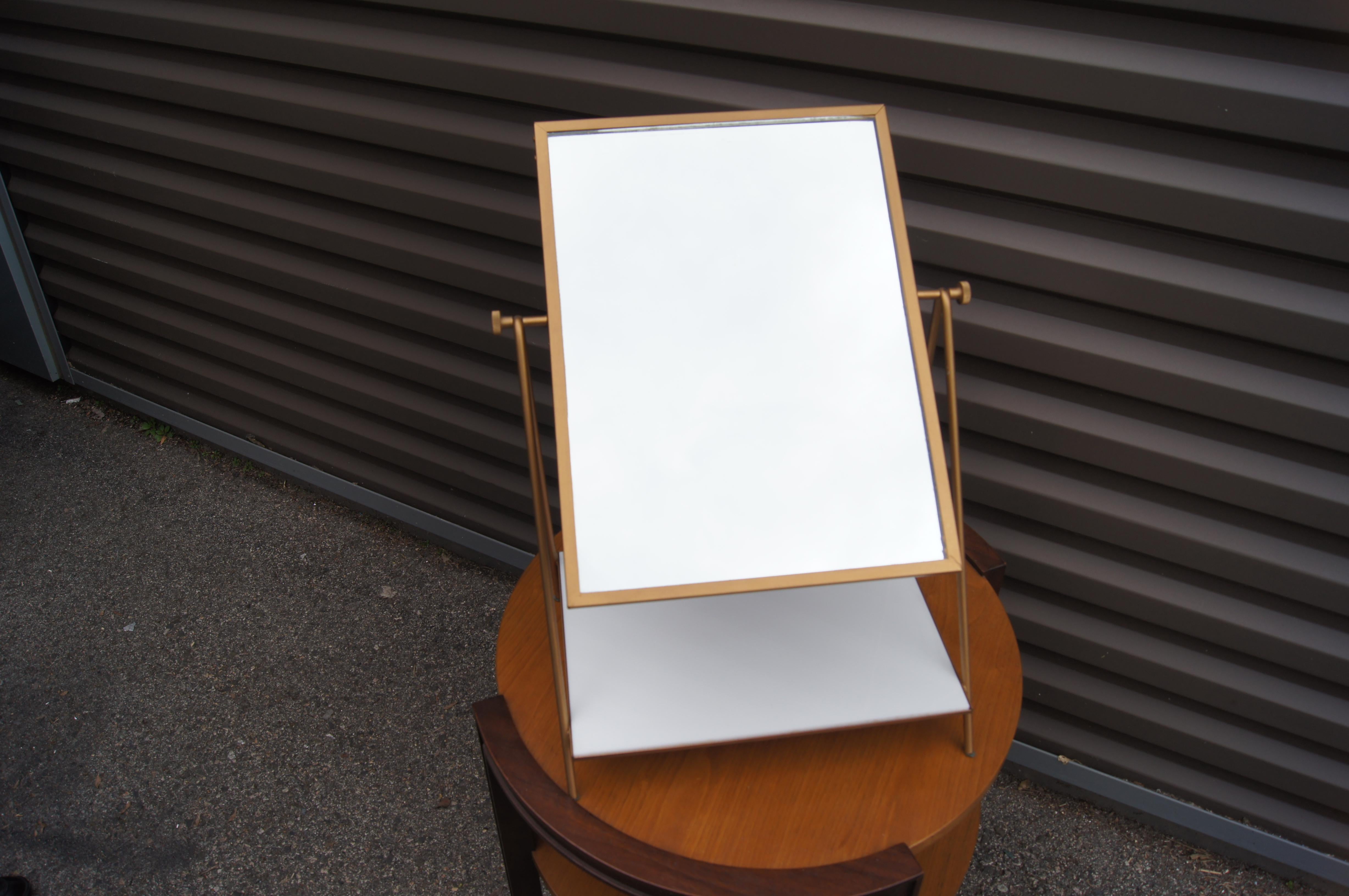 Designed by Paul McCobb for Bryce Originals, this elegant mid-century modern table mirror comprises a slender painted iron frame with a swiveling mirror and an inset white Vitrolite glass shelf. 

(Table not included.)