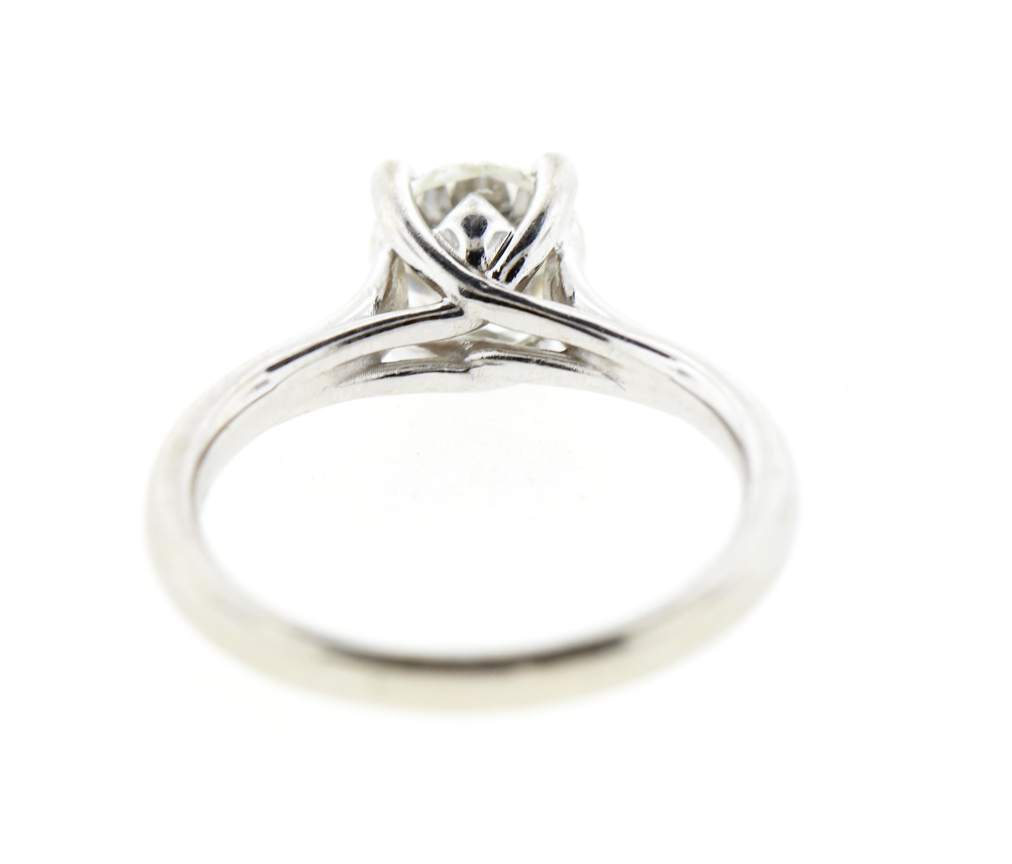 This swooping diamond solitaire engagement ring features a criss cross style basket that cradles the center diamond and features standard prongs. This ring can be customized for any shape center stone and made in any kind of metal, including white