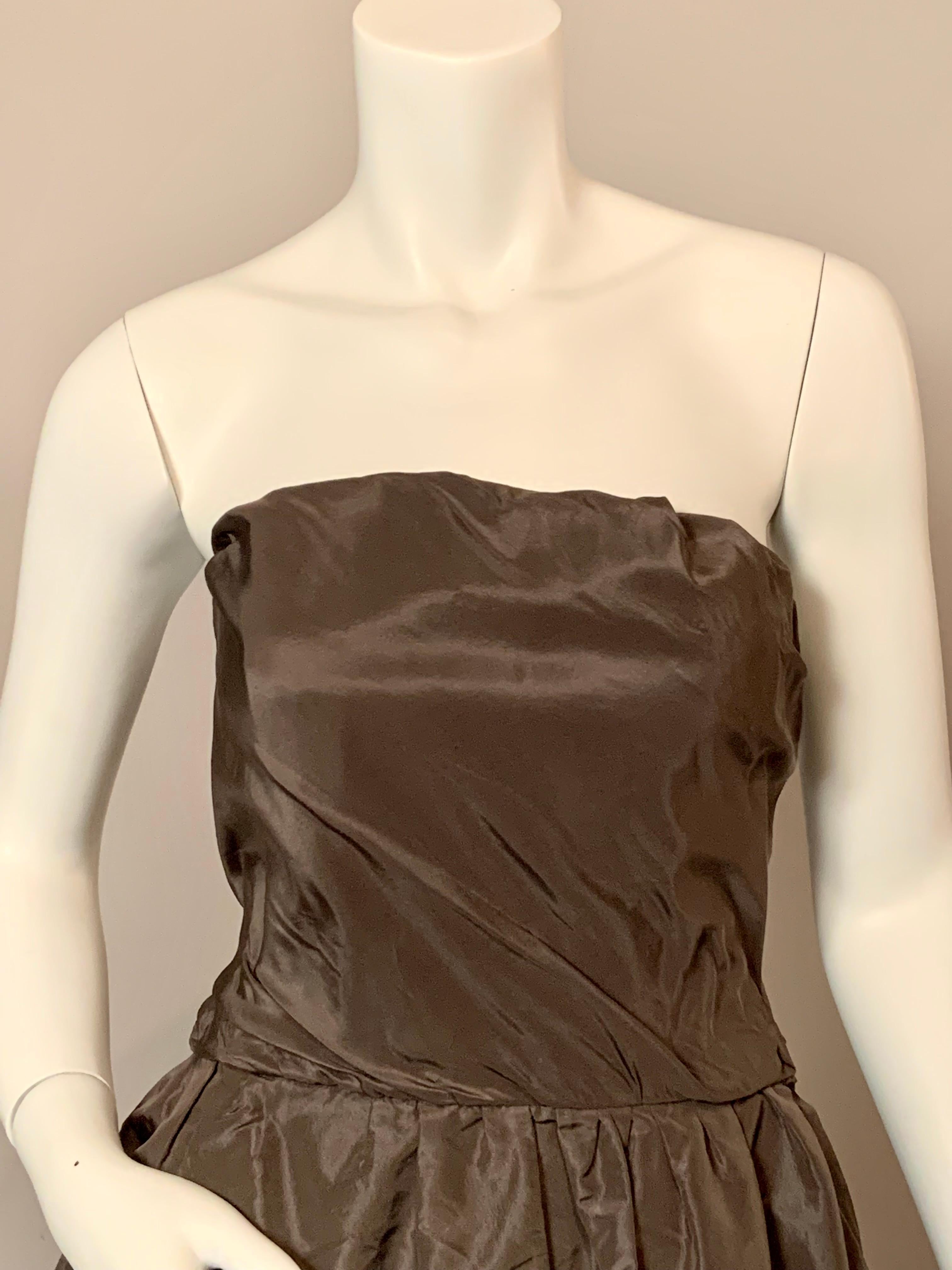 A chic charcoal grey gown with a hint of mauve, in a rich and rustling silk from Sybil Connolly, the Irish Couturier, is simple and elegant at the same time, a perfect jewelry dress.
The bodice has a chic drape and the full skirt is loosely gathered