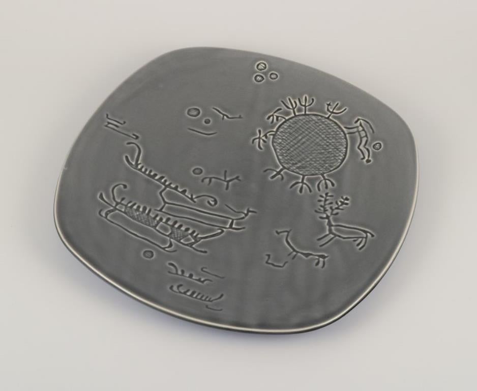 Syco, laboratorio di ceramica svedese.
Grande piatto decorativo con motivi di incisioni rupestri proveniente da Tanum, in Svezia.
Smaltato nei toni del grigio.
Circa 1970.
Contrassegnato.
In ottime condizioni, con incrinature naturali.
Dimensioni: D