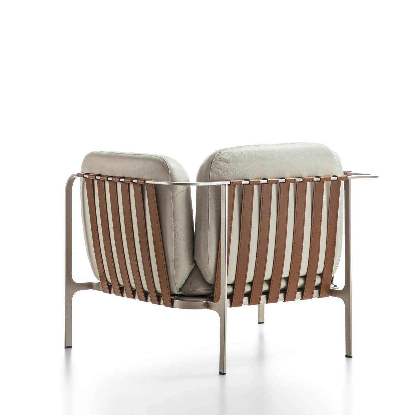 Der Sessel Sydney besteht aus einem schlanken Metallrohrgestell, das elegant lackiert und mit Lederriemen verziert ist, die ihm einen raffinierten Touch verleihen. Die Plüschkissen aus hochdichtem Polyurethanschaum sind mit luxuriösem, weichem