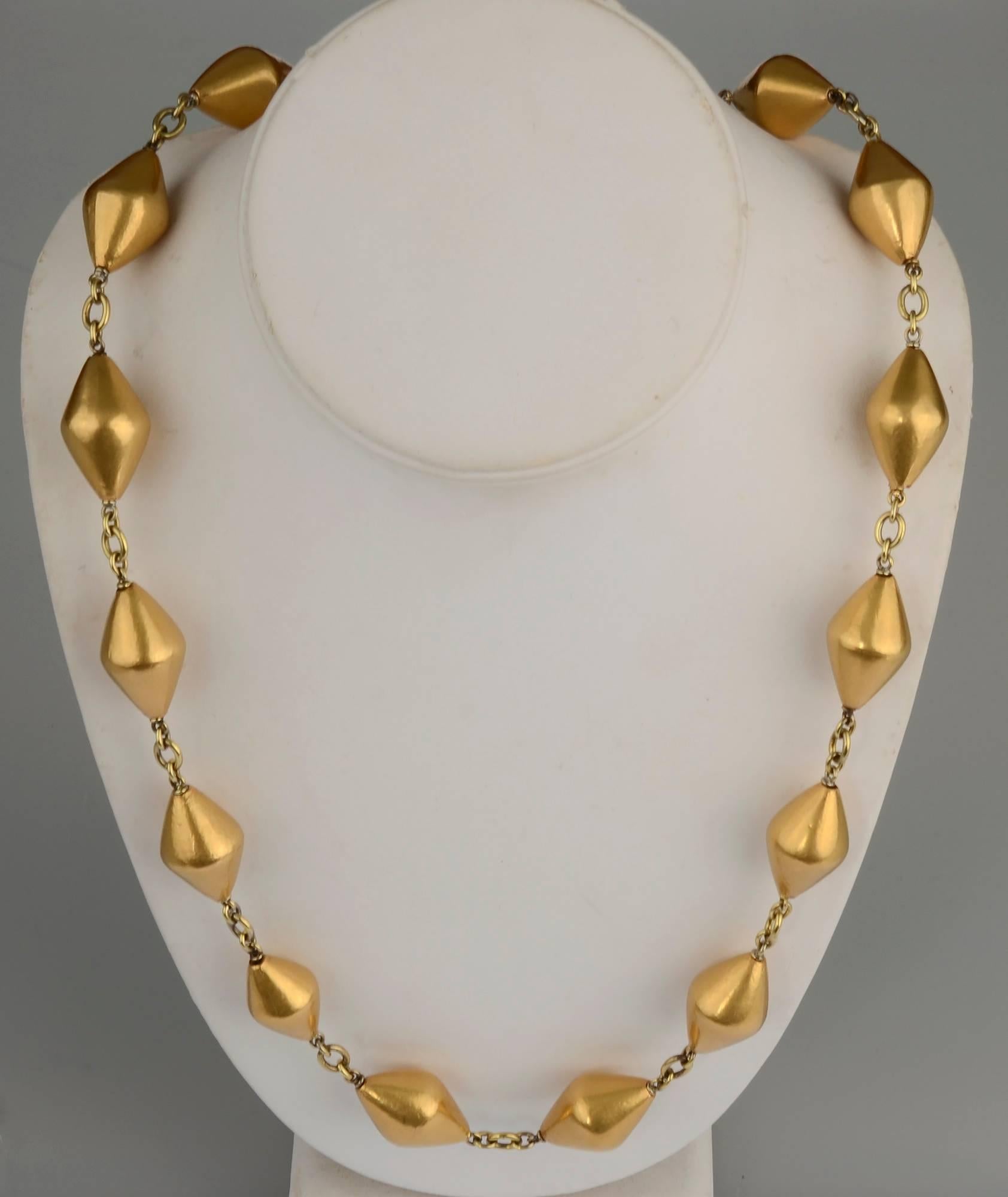 Unusual long chain necklace of 18 karat gold by Sylva et Cie. The 32 inch necklace is made of 20 rhombus shaped beads connected with round and oval links. It has a beautiful detailed clasp with floral patterning. 