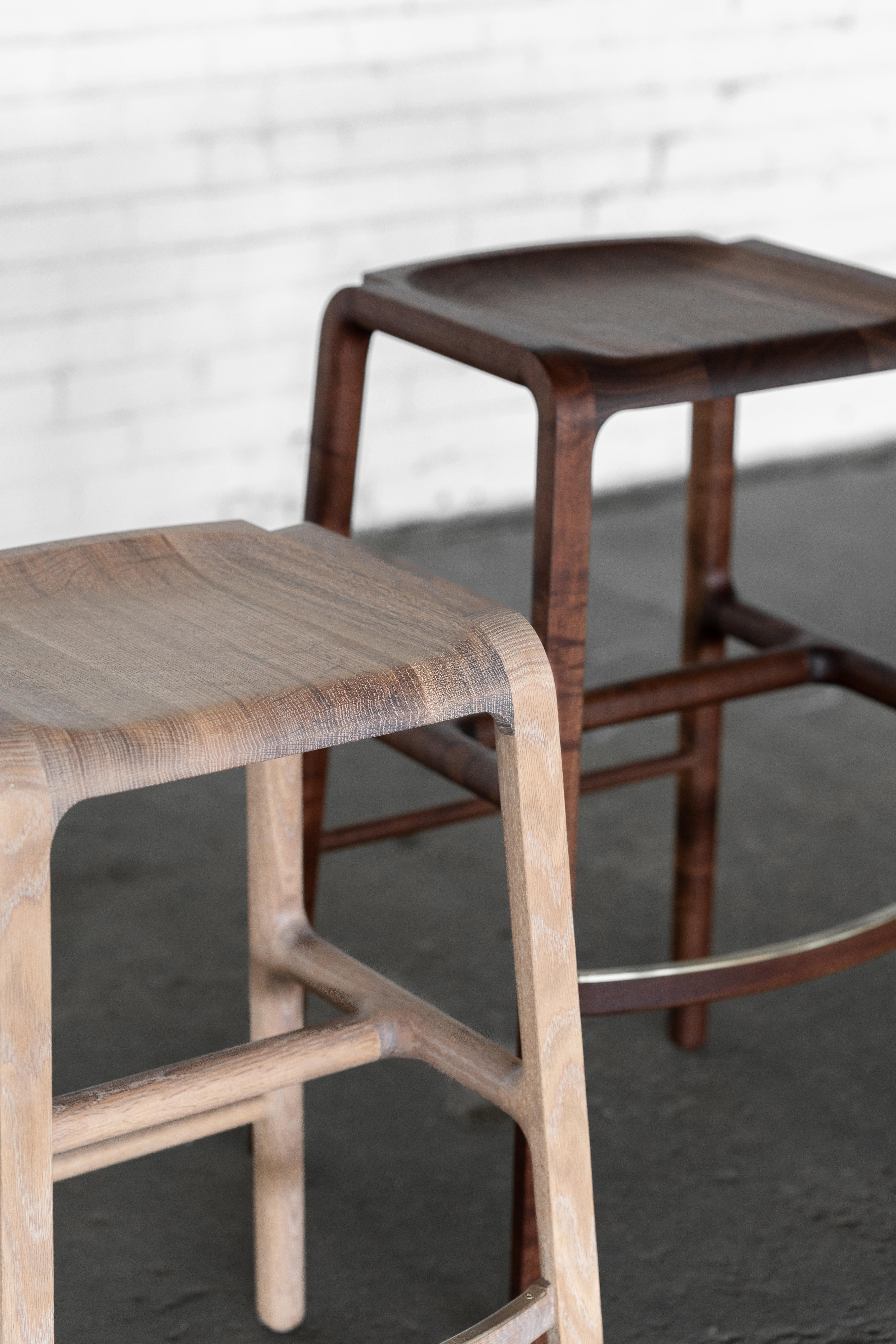 Cette pièce est un tabouret tout en bois avec de subtils détails en laiton.  Notre objectif était de créer une forme moderne unique qui mette en valeur les détails du bois dur naturel tout en faisant écho au charme intemporel de nos chaises Estrada