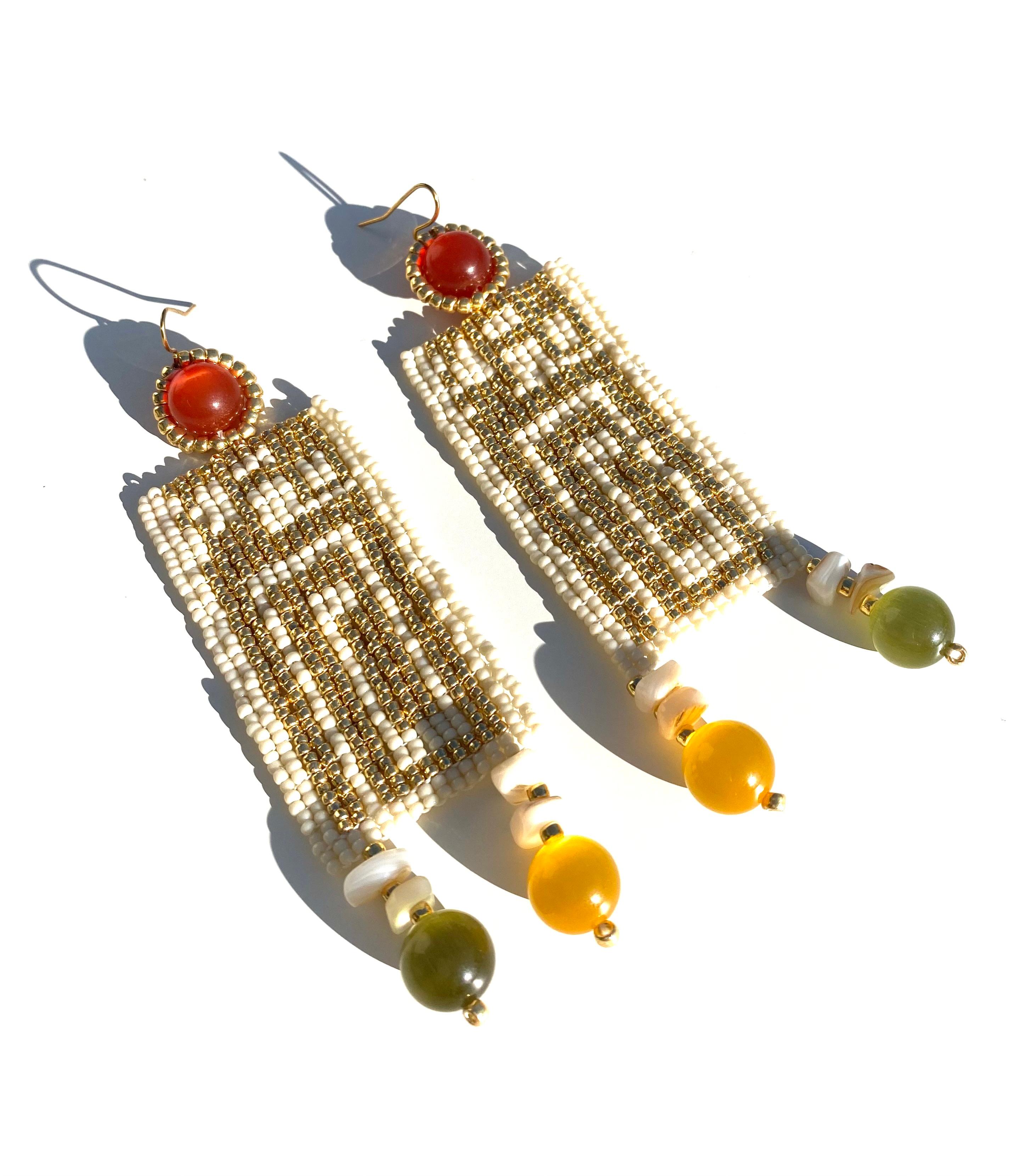 Handwoven pattern in 14k permanent gold-plated glass Japanese seed beads and ivory white seed beads.  Cat's eye glass breads in marigold and olive green and conch shell beads. Gold filled ear wires. 
Inspired by puertorican innovative and iconic