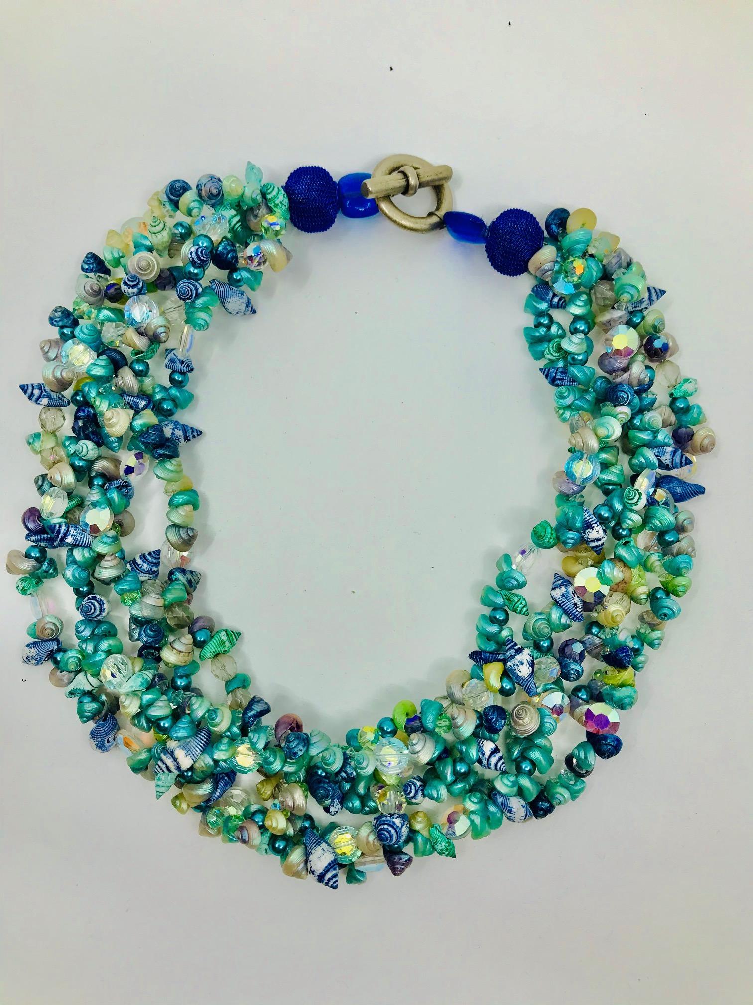 This statement  necklace consists of 5 strands of tiny shells and Swarovski beads ,finished by larger blue beads and silvered clasp. Tiny shells are rom Tasmania . In the past they were collected by Aboriginal women for their daughters wedding