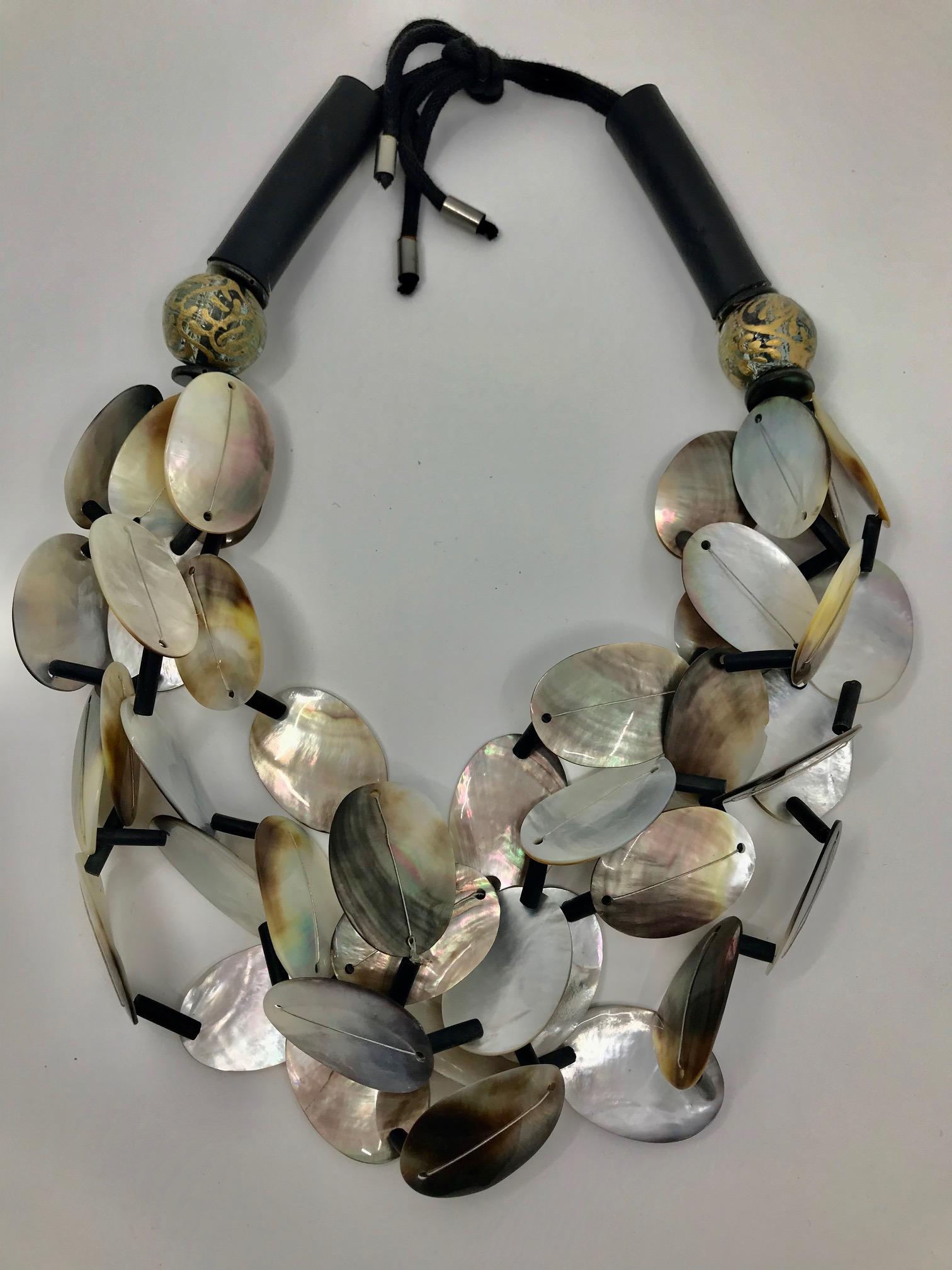 Black Mother of Pearl MultI ,4 strand Statement necklace , consists of large oval black M.O.P beads arranged  in three dimensional fashion. Black wooden tubular beads are used as spacers and the ends are finished with large ,in gold hand painted