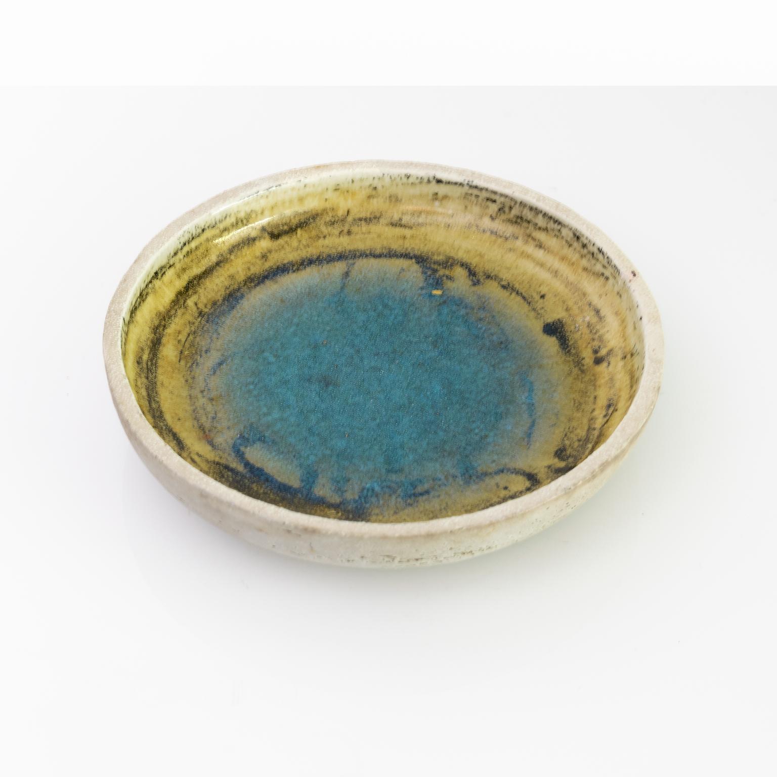Una ciotola da studio unica di Sylvia Leuchovious con una pozza di smalto blu acqua al centro. La ciotola è realizzata a mano e in argilla charmotte. Realizzato a Gustavsberg, circa 1960.

Misure: Diametro: 10 Altezza: 2