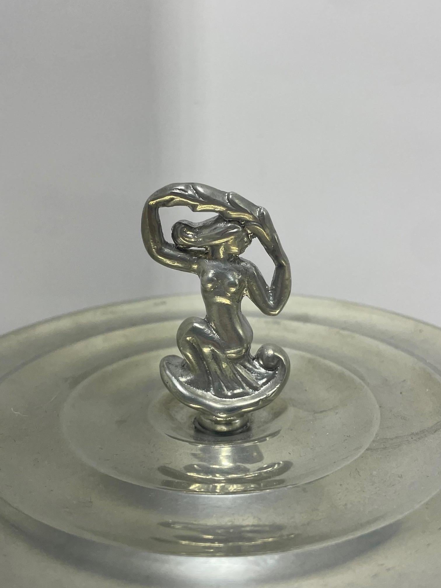 Esta exquisita caja de peltre con tapa, diseñada por la sueca Sylvia Stave en 1928, ejemplifica el refinado minimalismo y la elegancia escultórica del modernismo escandinavo. Apoyada sobre tres pies esféricos, la forma redondeada está sutilmente