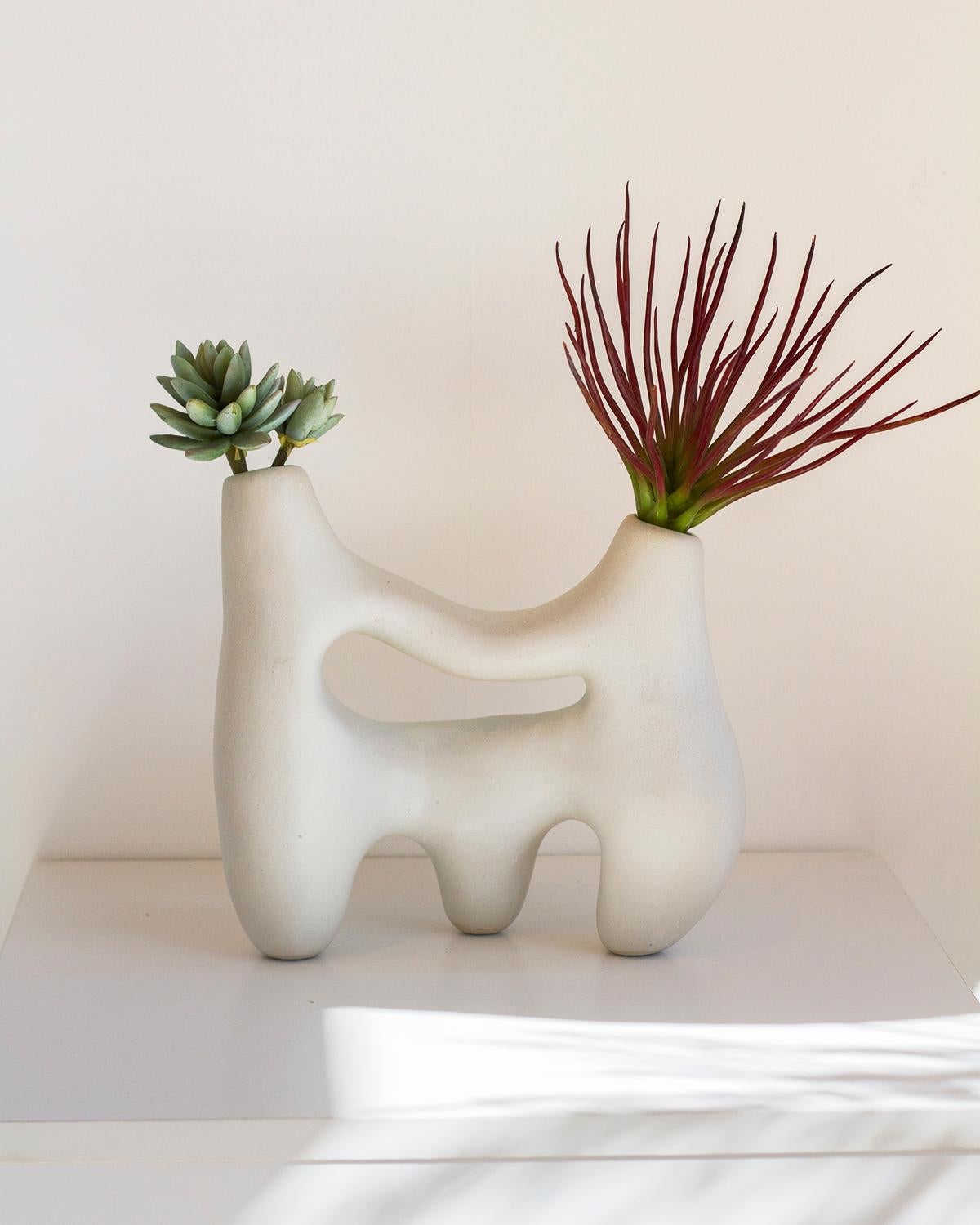 Ce vase en argile Symbiosis est un vase sculptural unique en argile blanche. Son aspect à la fois rustique et minimaliste convient parfaitement aux décors organiques, modernes et futuristes. Fabriqué à la main avec soin, ce vase en os blanc
