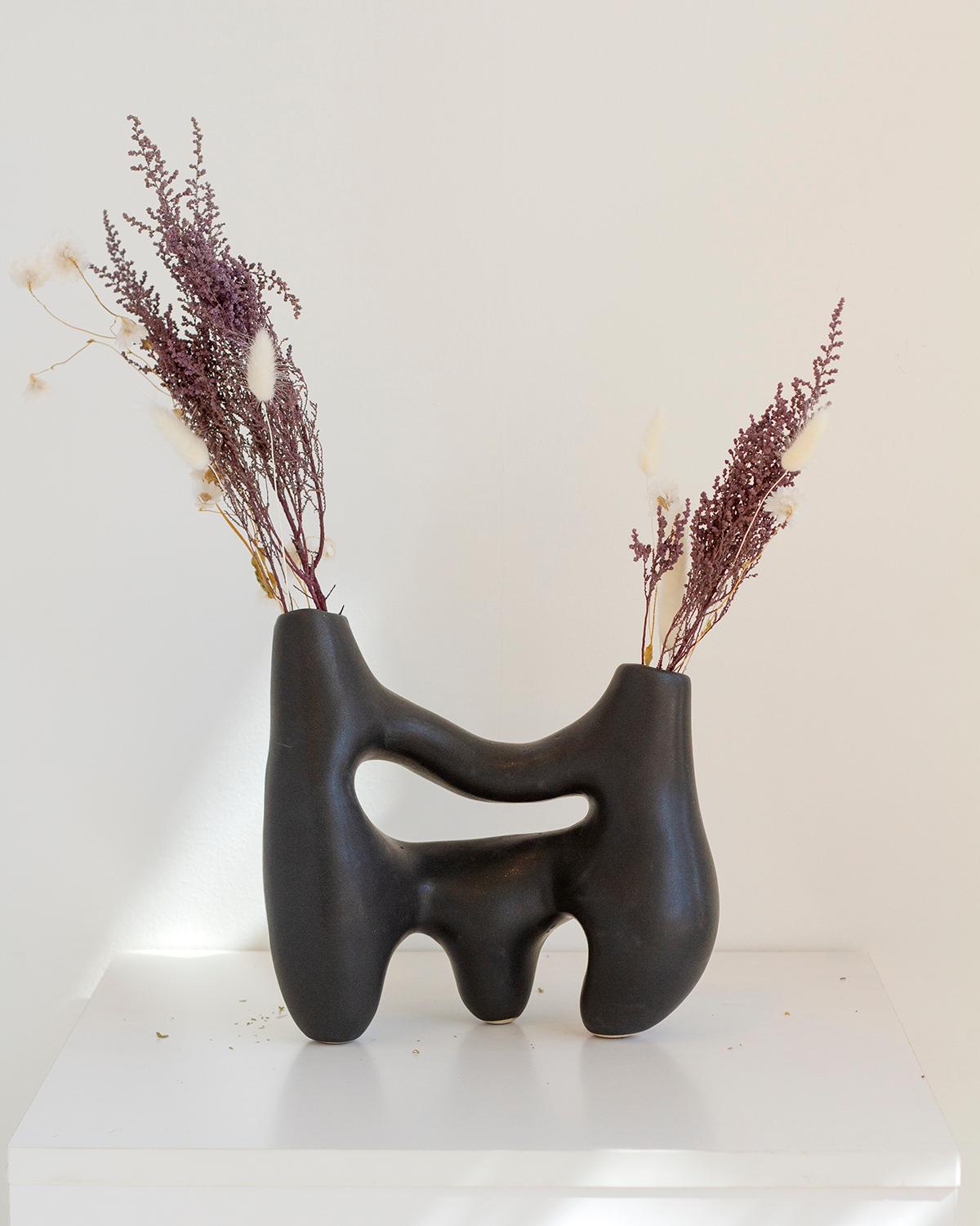 Ce vase unique en argile fait à la main est un cadeau idéal pour les fêtes de fin d'année. Avec son design sculptural et minimaliste et sa couleur noir charbon, il ajoute une touche de luxe tranquille et rustique à n'importe quelle pièce. Chaque