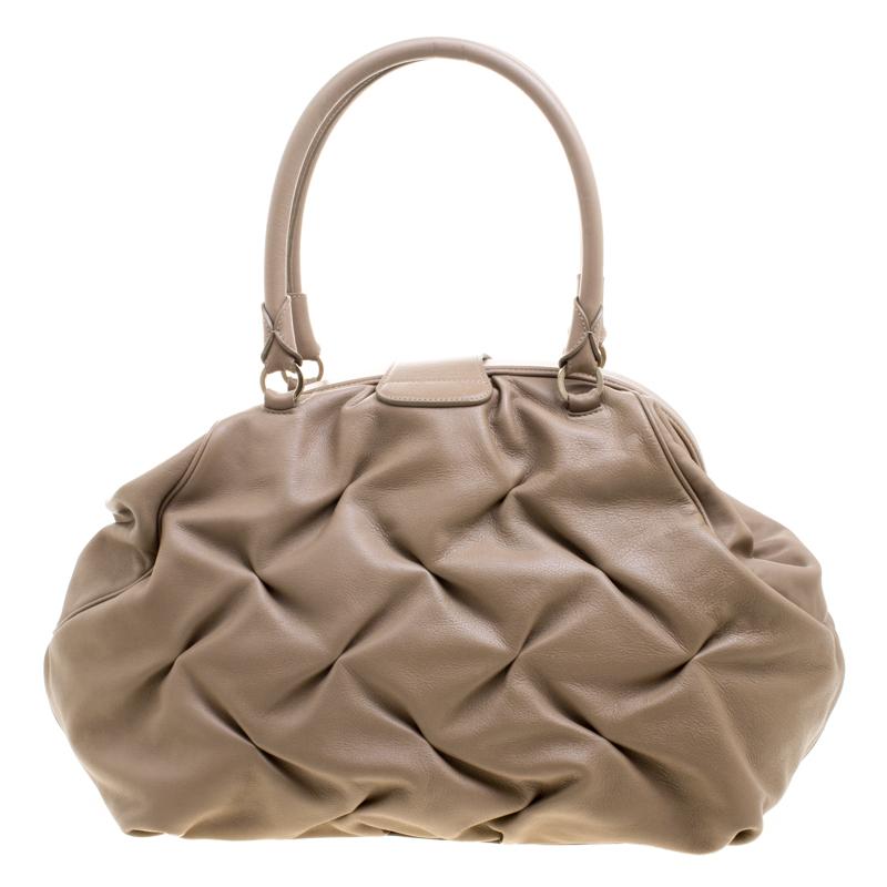 Sophisticated and feminine, this Nancy bag from the house of Symthson features a supple beige leather body with a criss-cross pattern making it a notice-worthy piece. It comes fitted with two rolled top handles and a sturdy top. This bag opens to